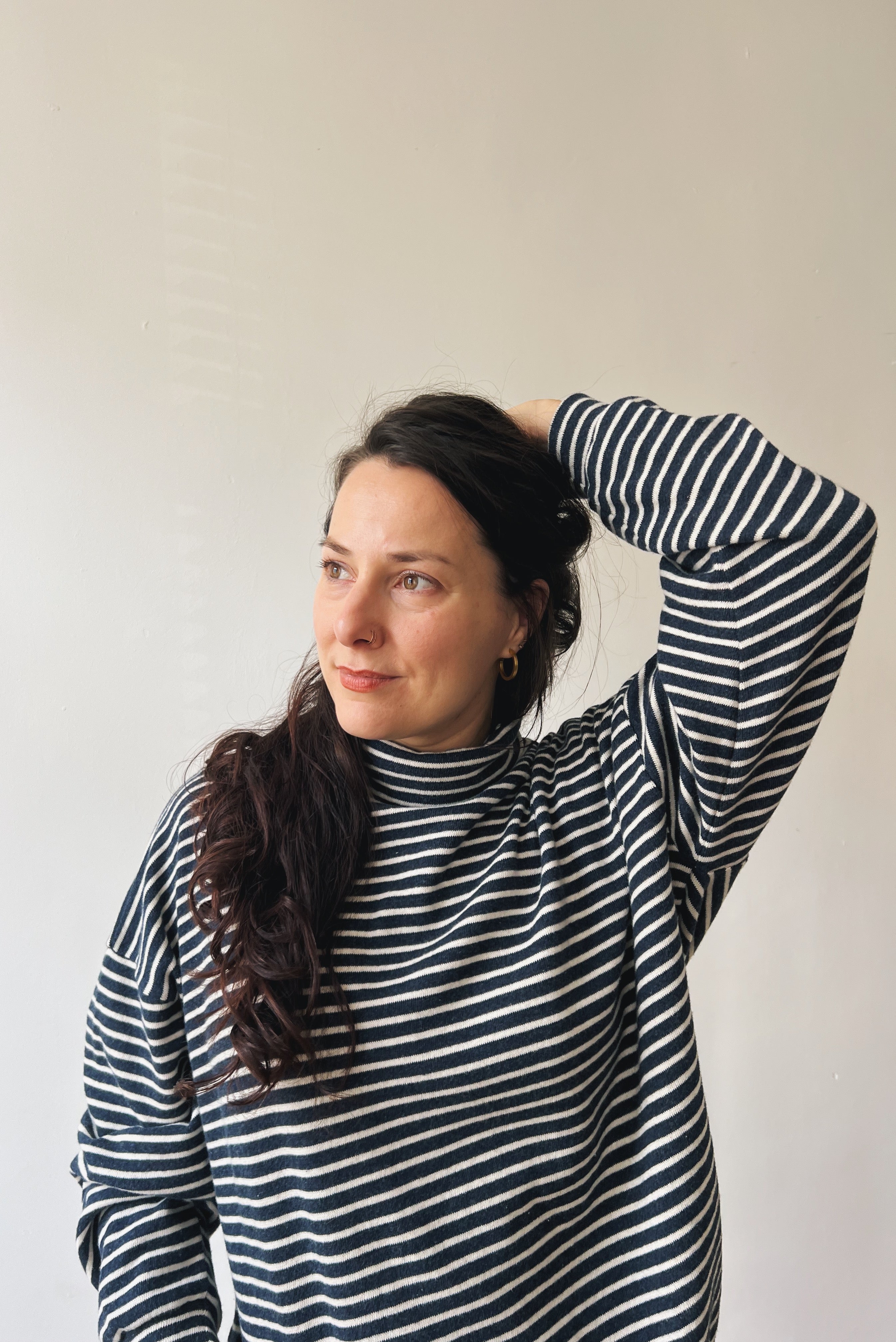 Woman wearing a blue and white striped sweater against a plain background
