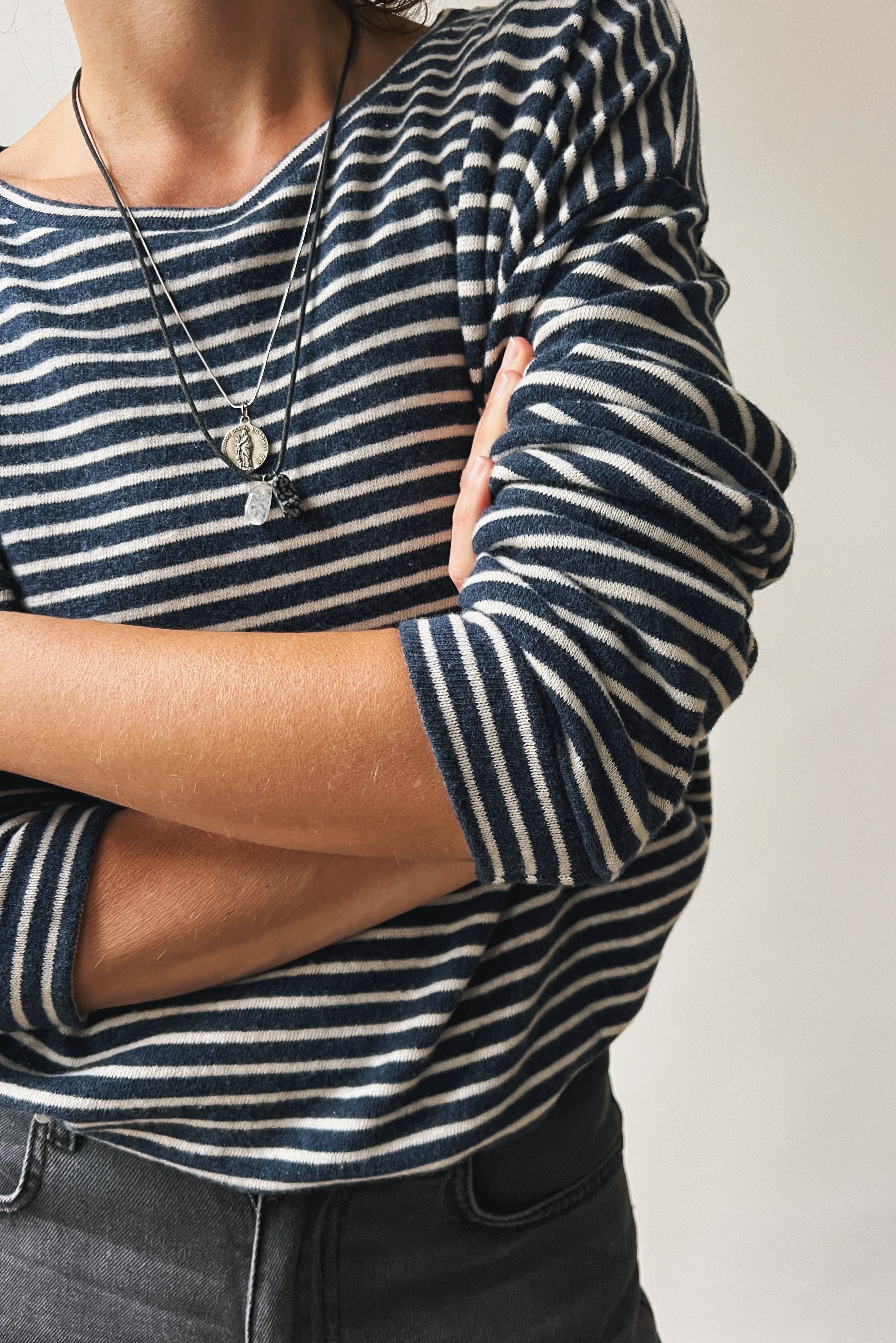 Person wearing a navy and white striped sweater with arms crossed against a neutral background