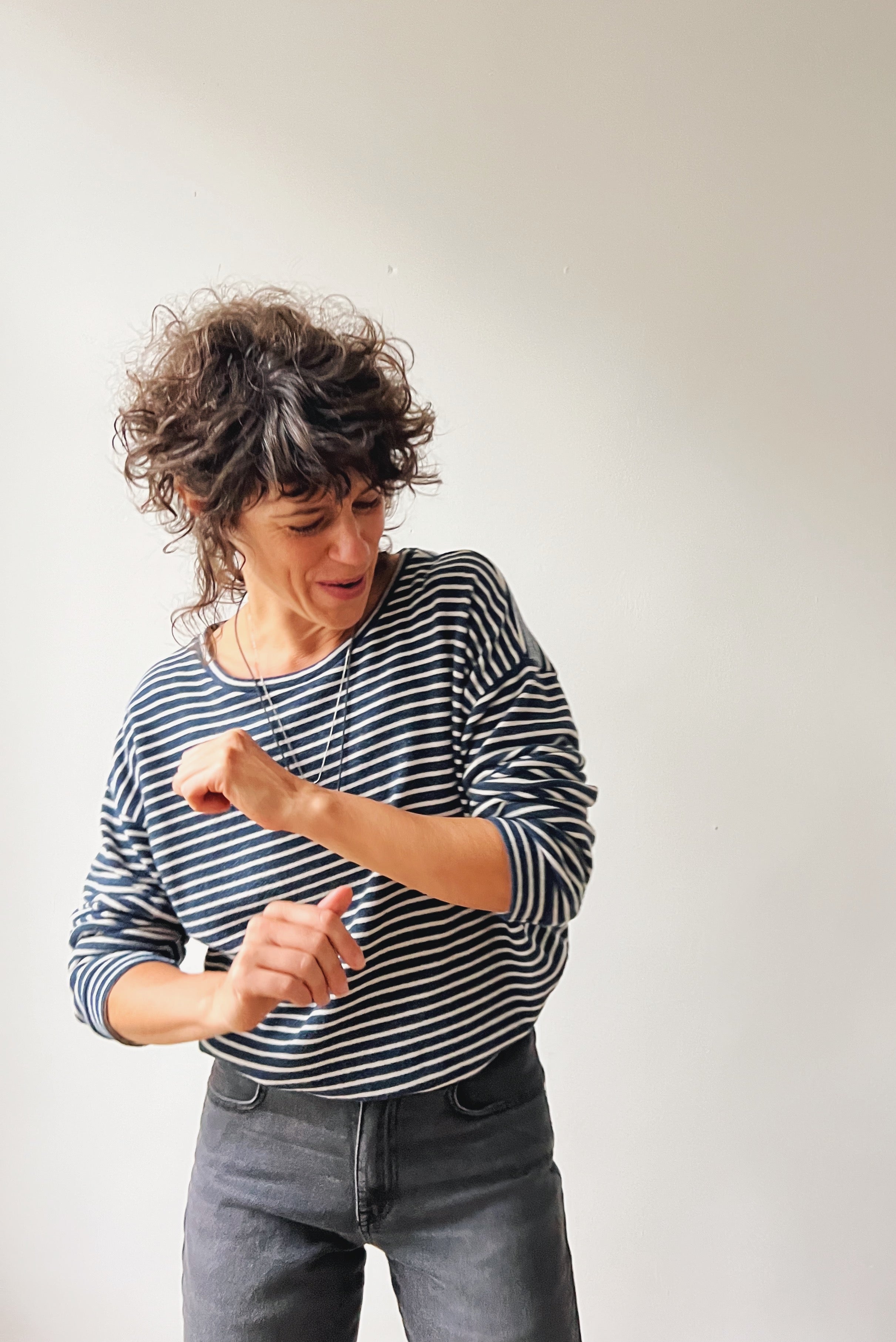 Person wearing a striped longsleeve and jeans against a plain background