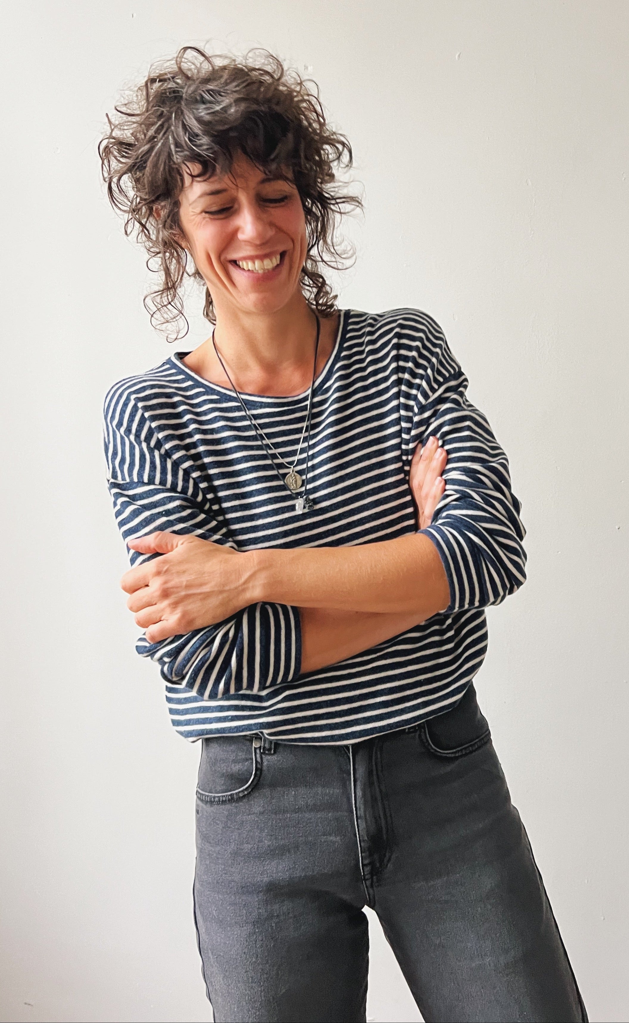 Woman wearing a striped shirt and jeans against a plain background