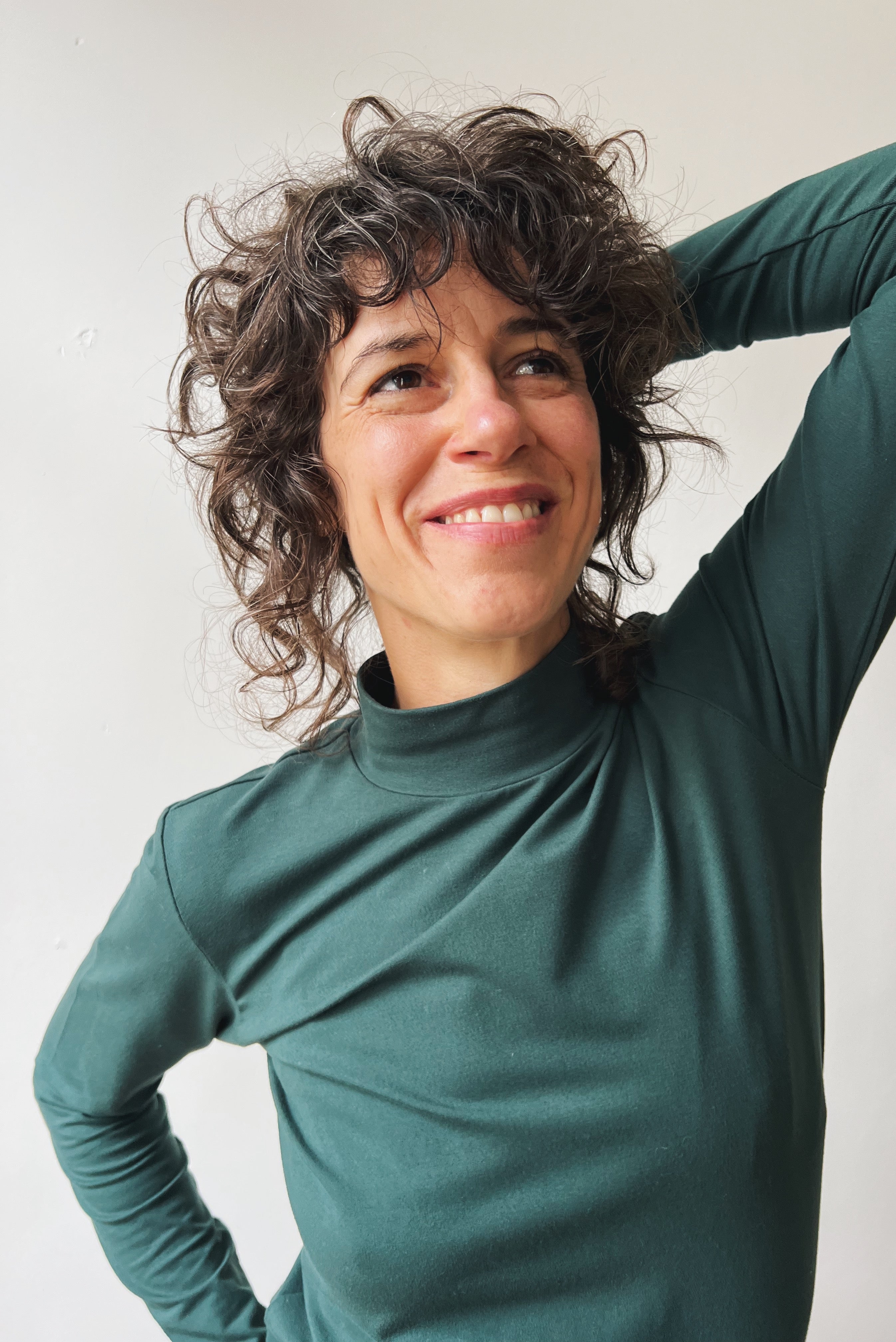Person wearing a pine turtleneck shirt against a plain background