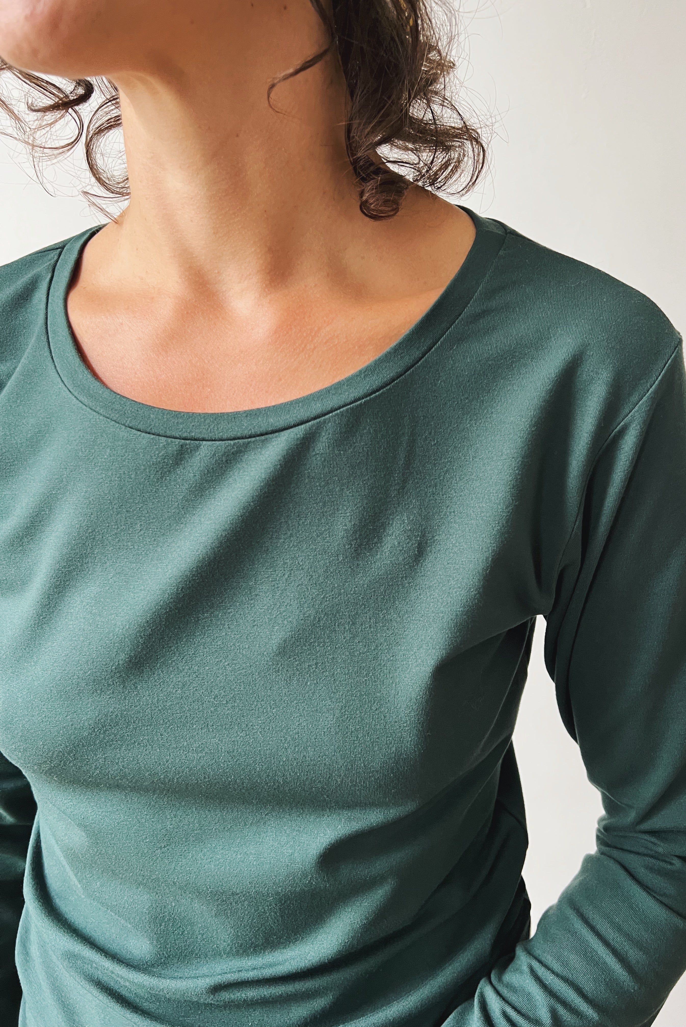 Woman wearing a pine long-sleeve against a plain background