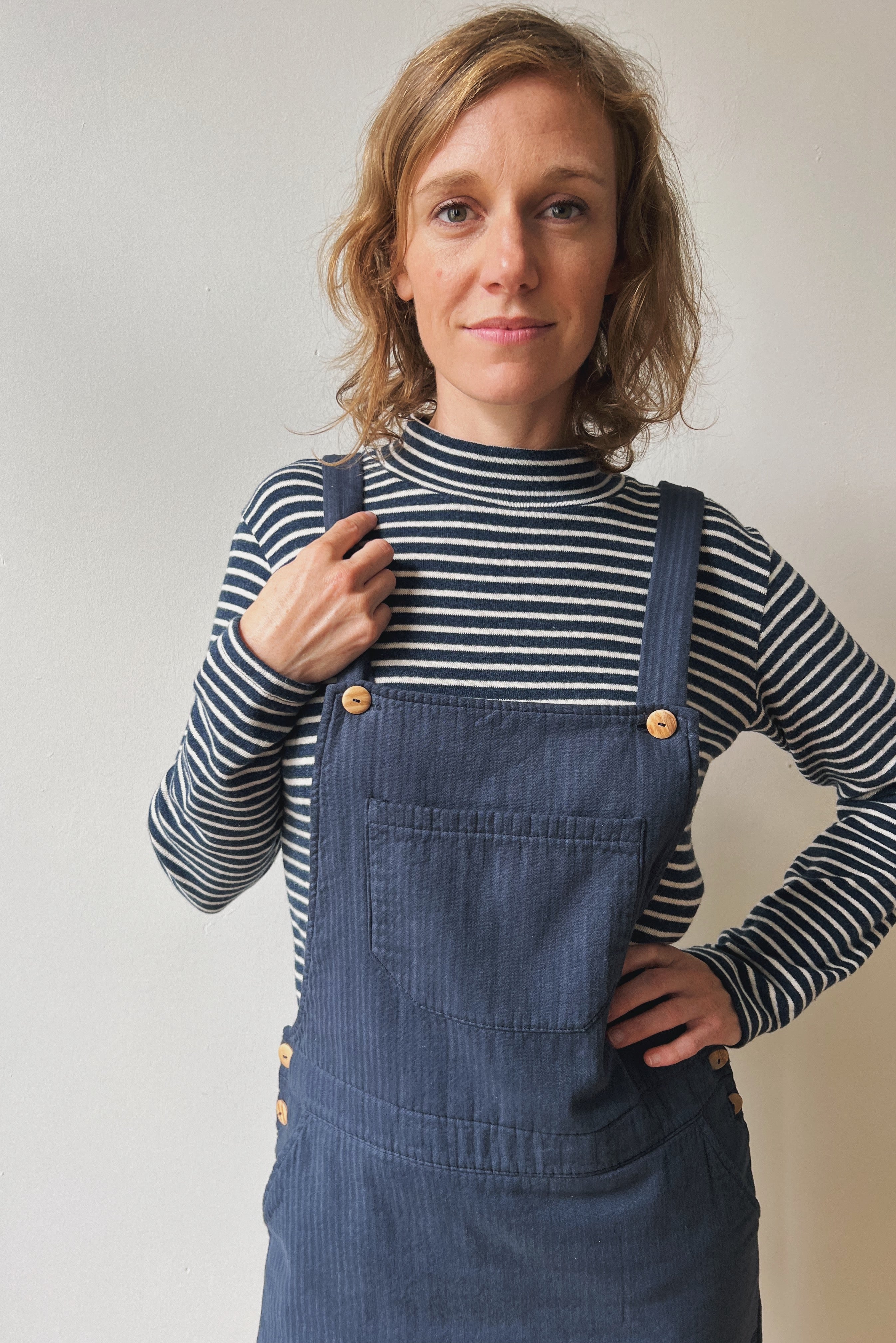 Woman wearing a blue-white striped turtleneck and blue salopettedress