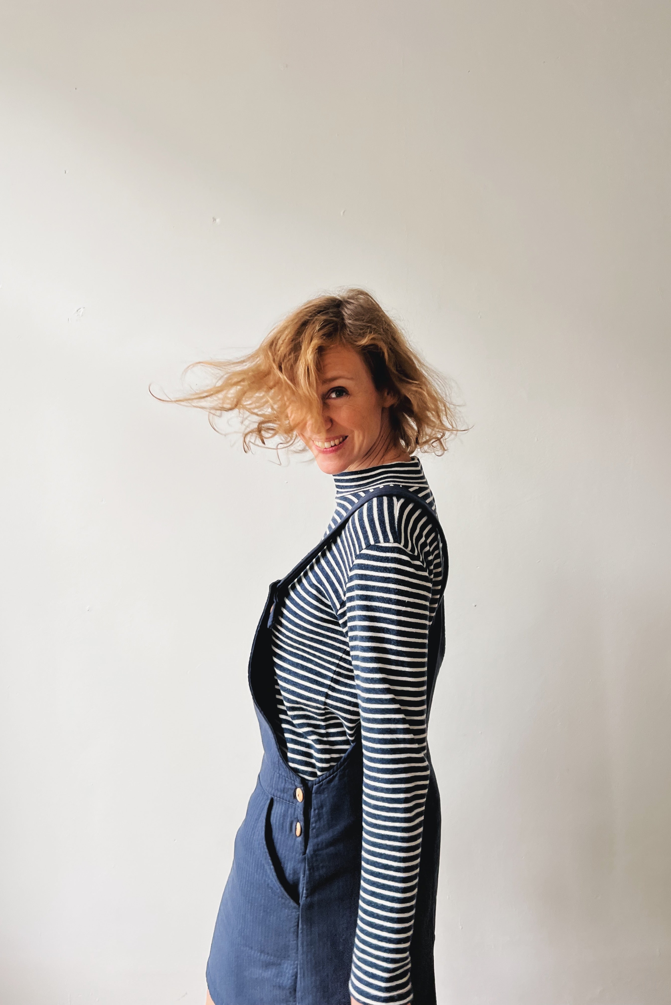 Woman wearing a blue-white striped turtleneck and blue salopettedress