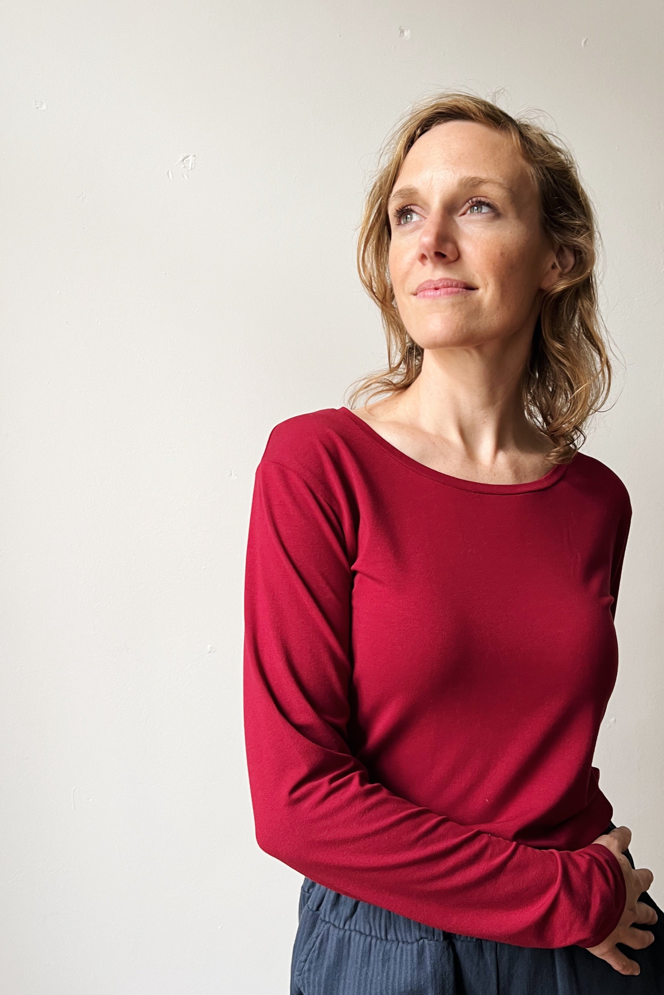 Woman wearing a red longsleeve against a plain background