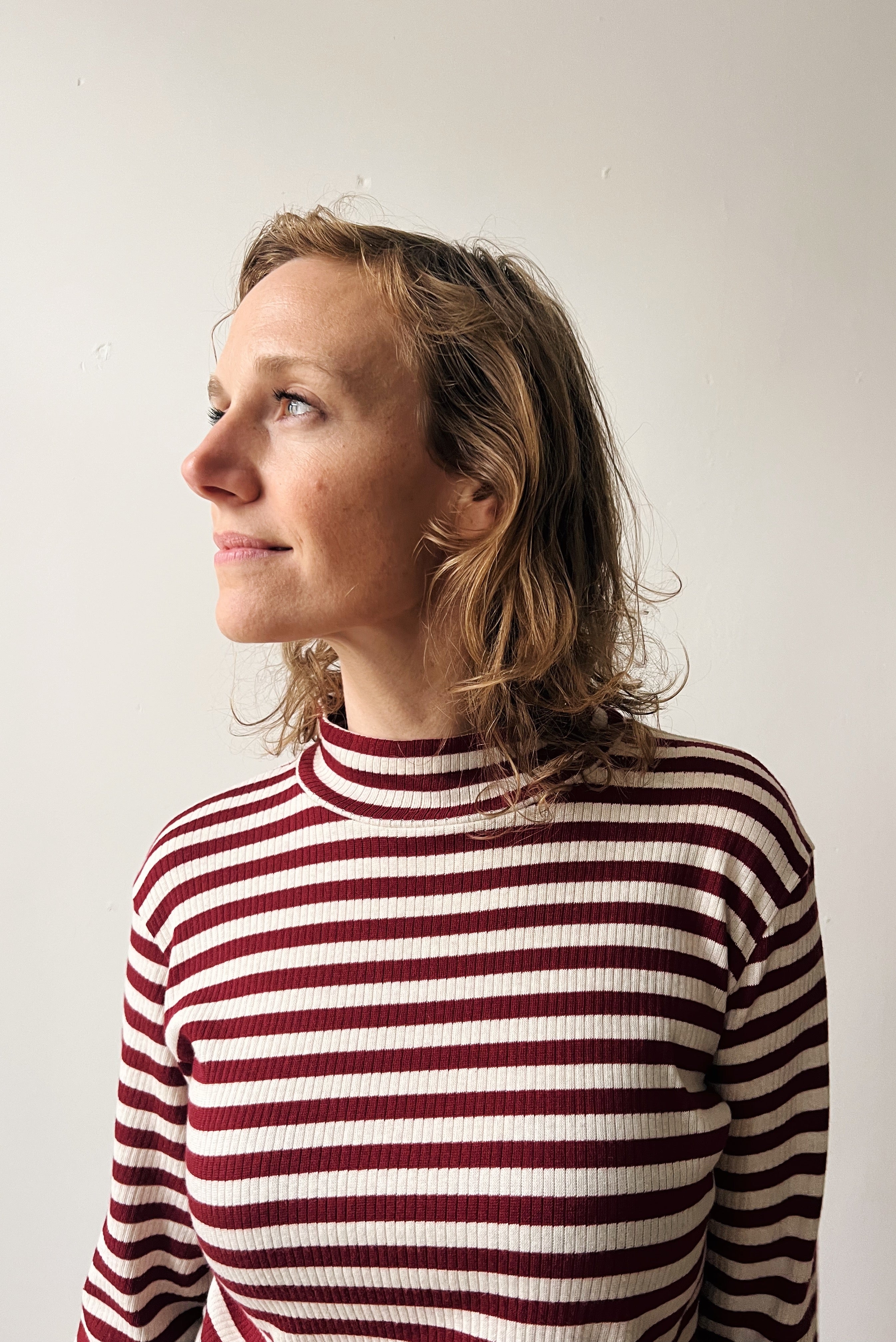 Woman wearing a red and white striped turtleneck against a plain background