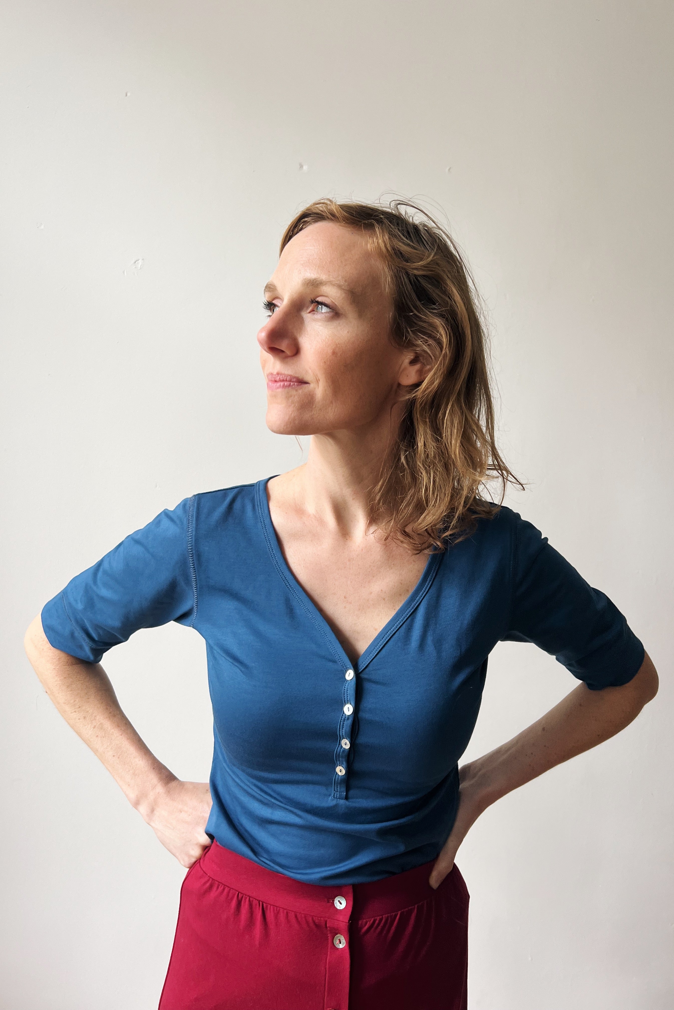 Woman wearing a blue top and red skirt with a white background