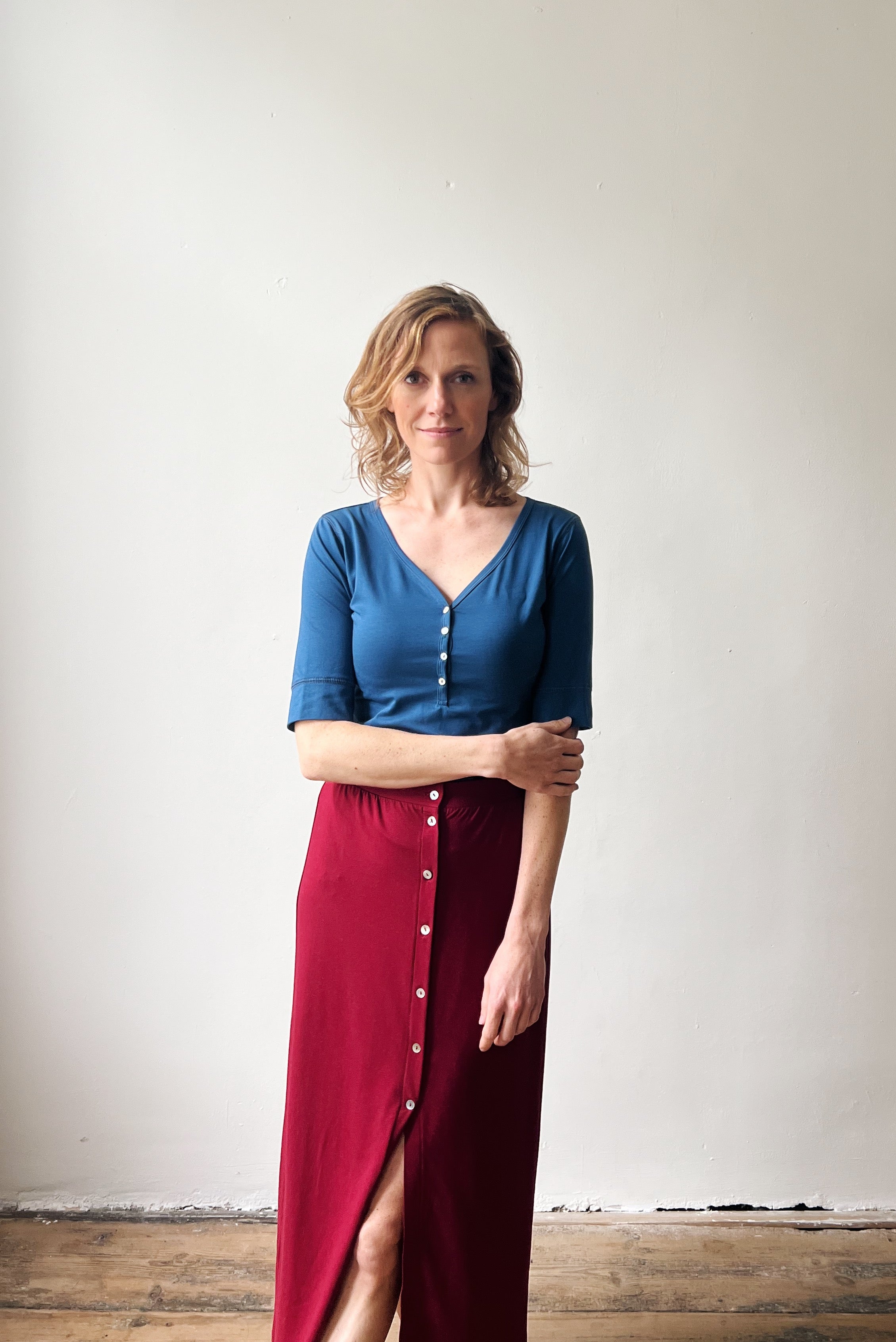 Woman wearing a blue top and red skirt against a plain background