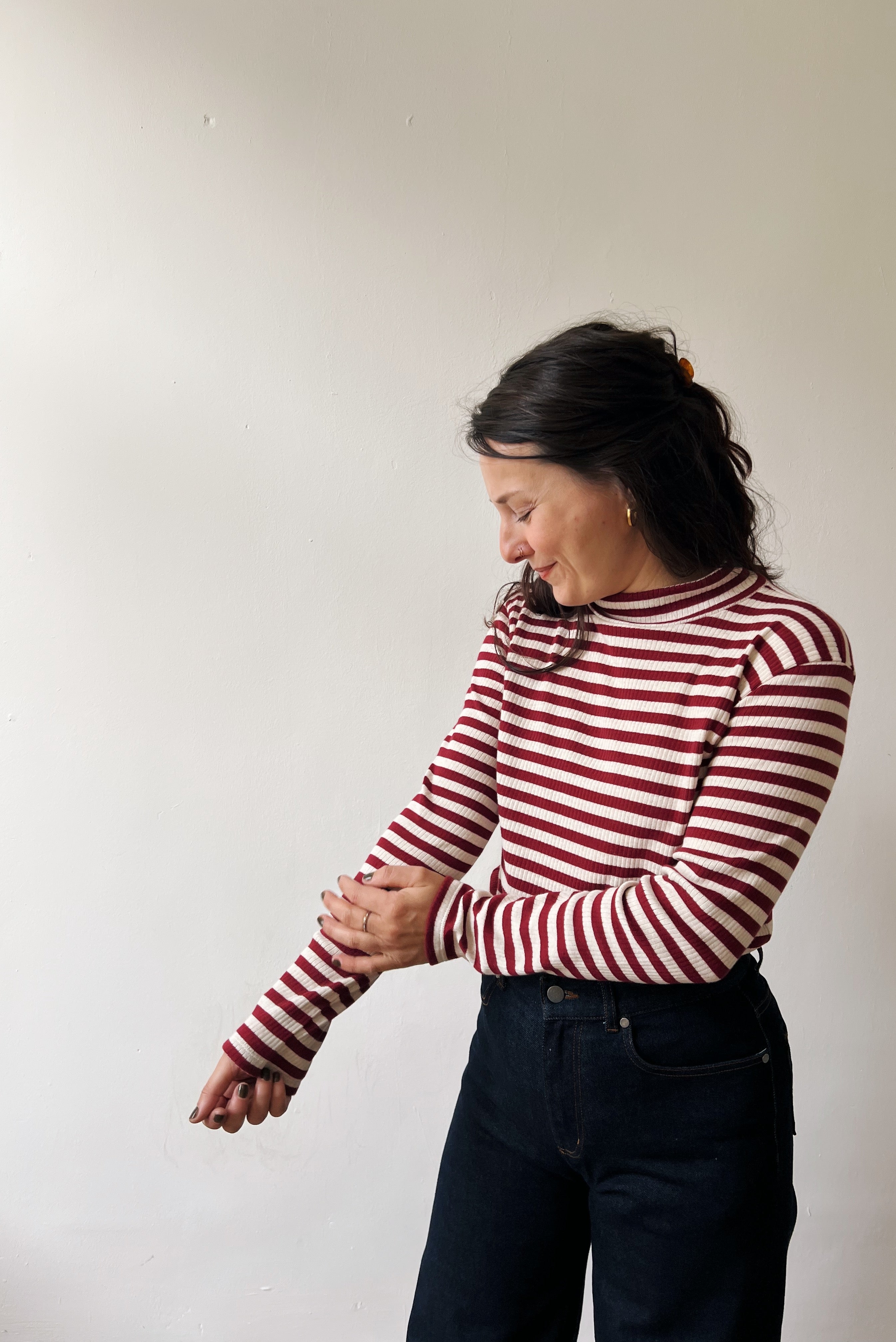 Woman wearing a red and white striped turtleneck against a plain background