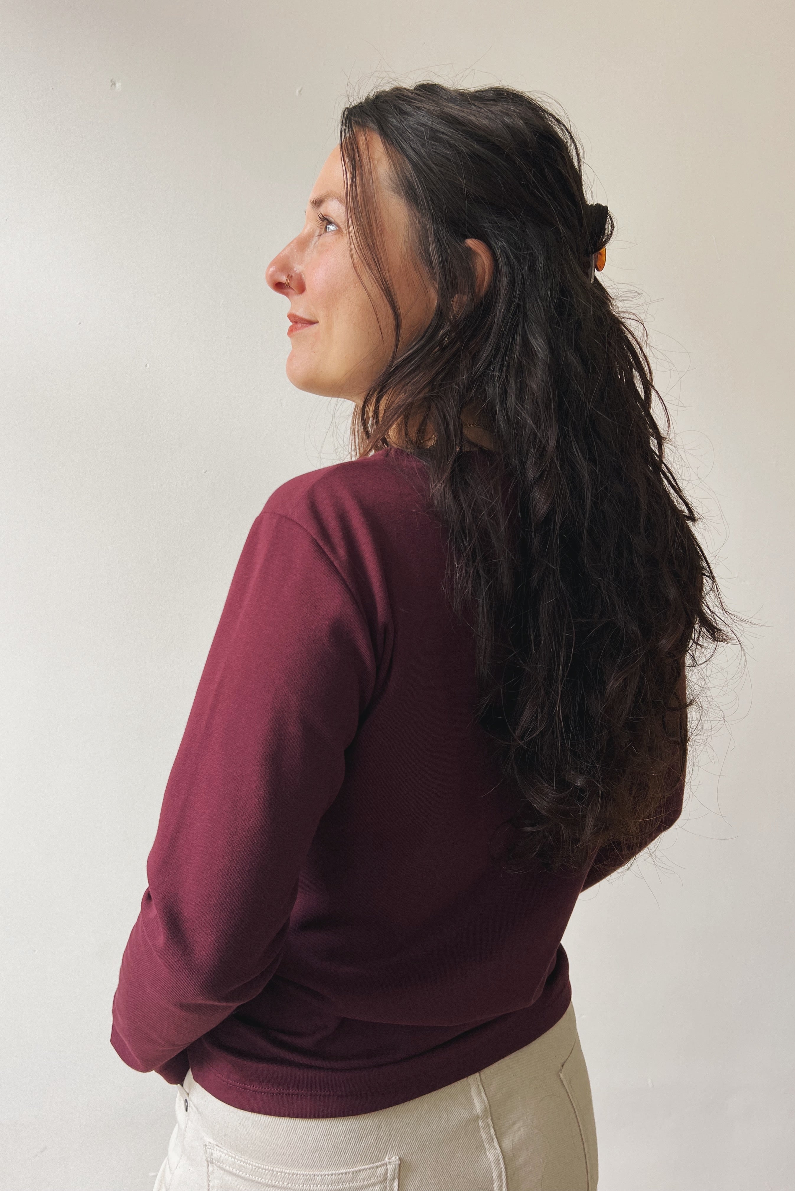 Woman wearing an aubergine longsleeve against a plain background