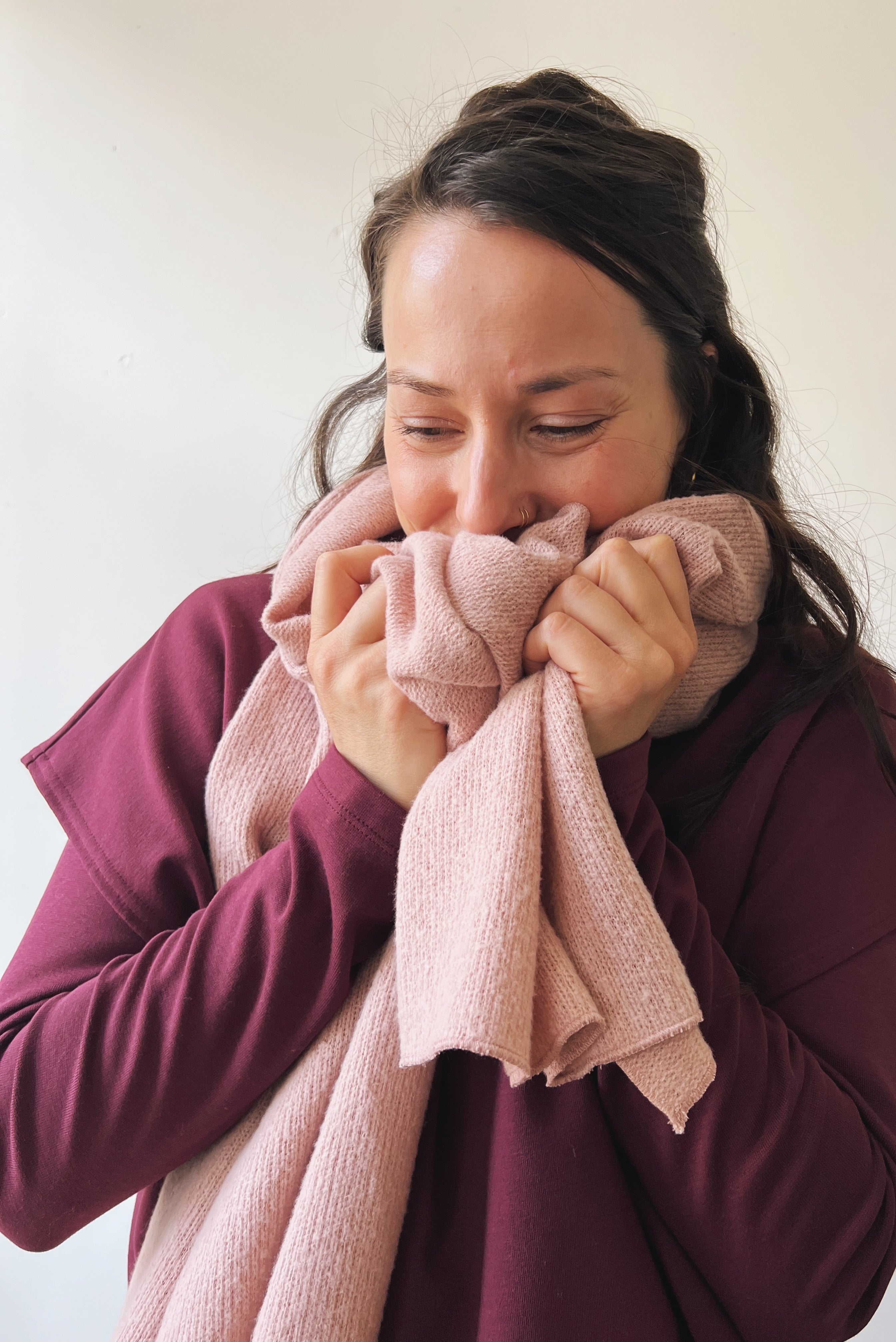 Woman hugging a pink scarf and purple sweater