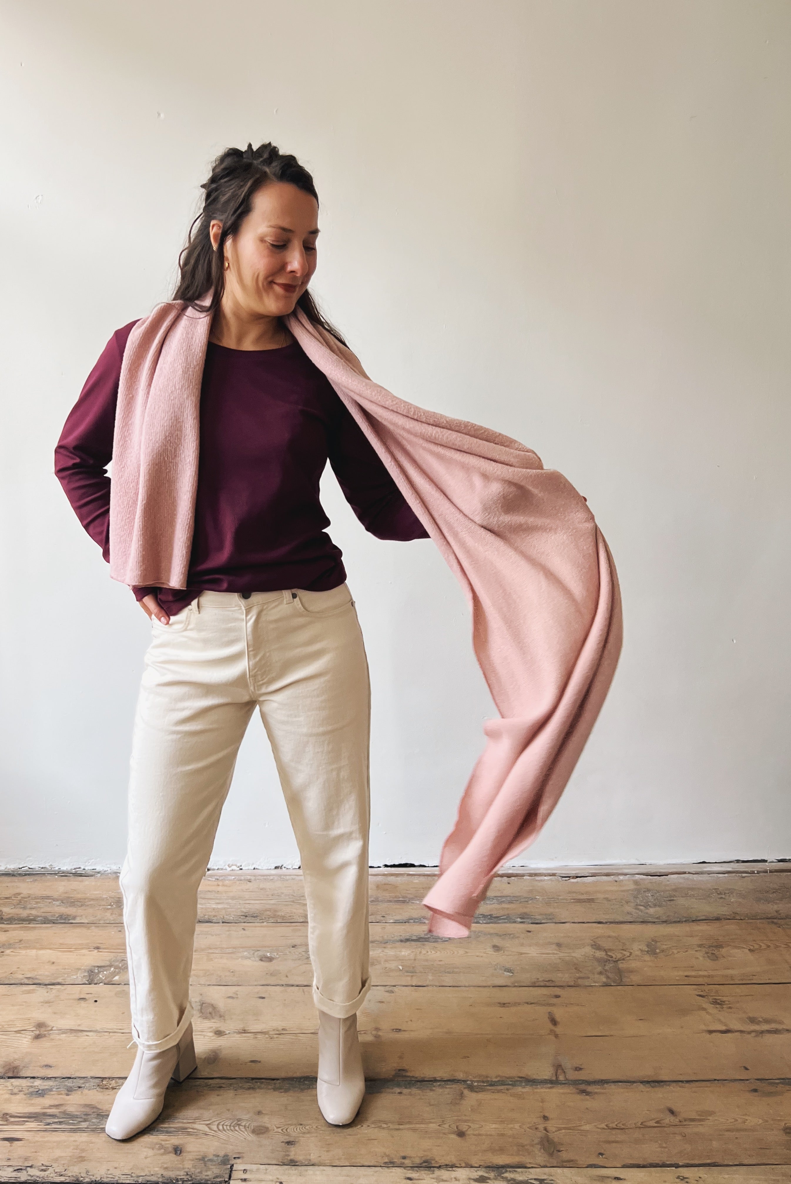 Woman wearing a pink scarf, aubergine longsleeve and oat boyfriend jeans.