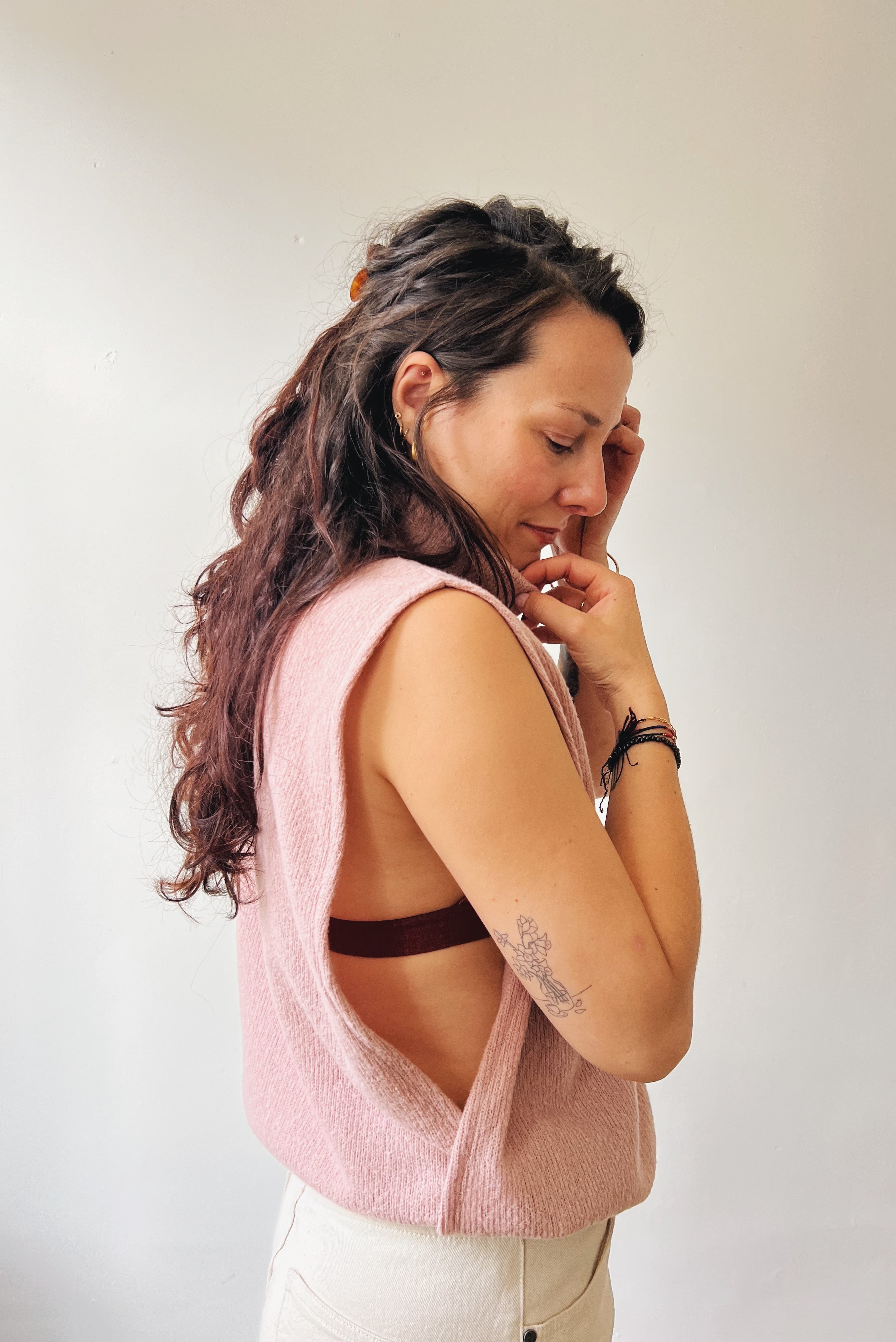 Woman wearing a pink sleeveless top with a white background