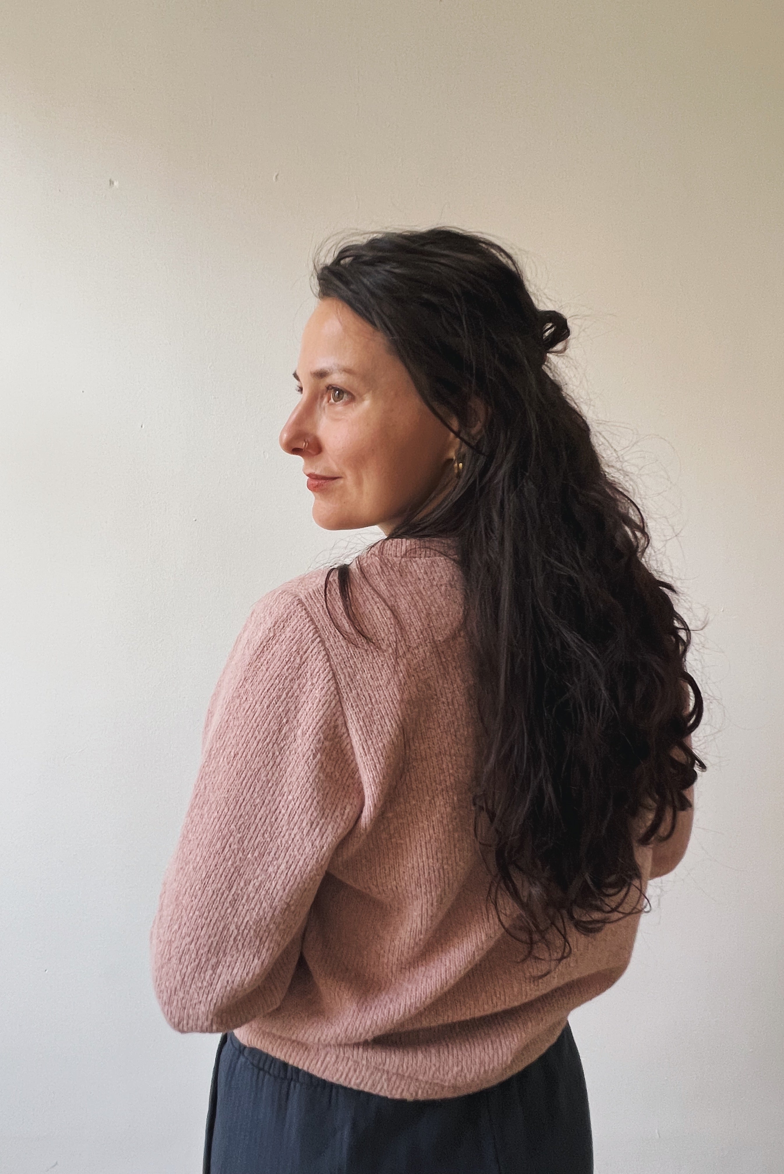 Woman wearing a pink sweater against a plain background