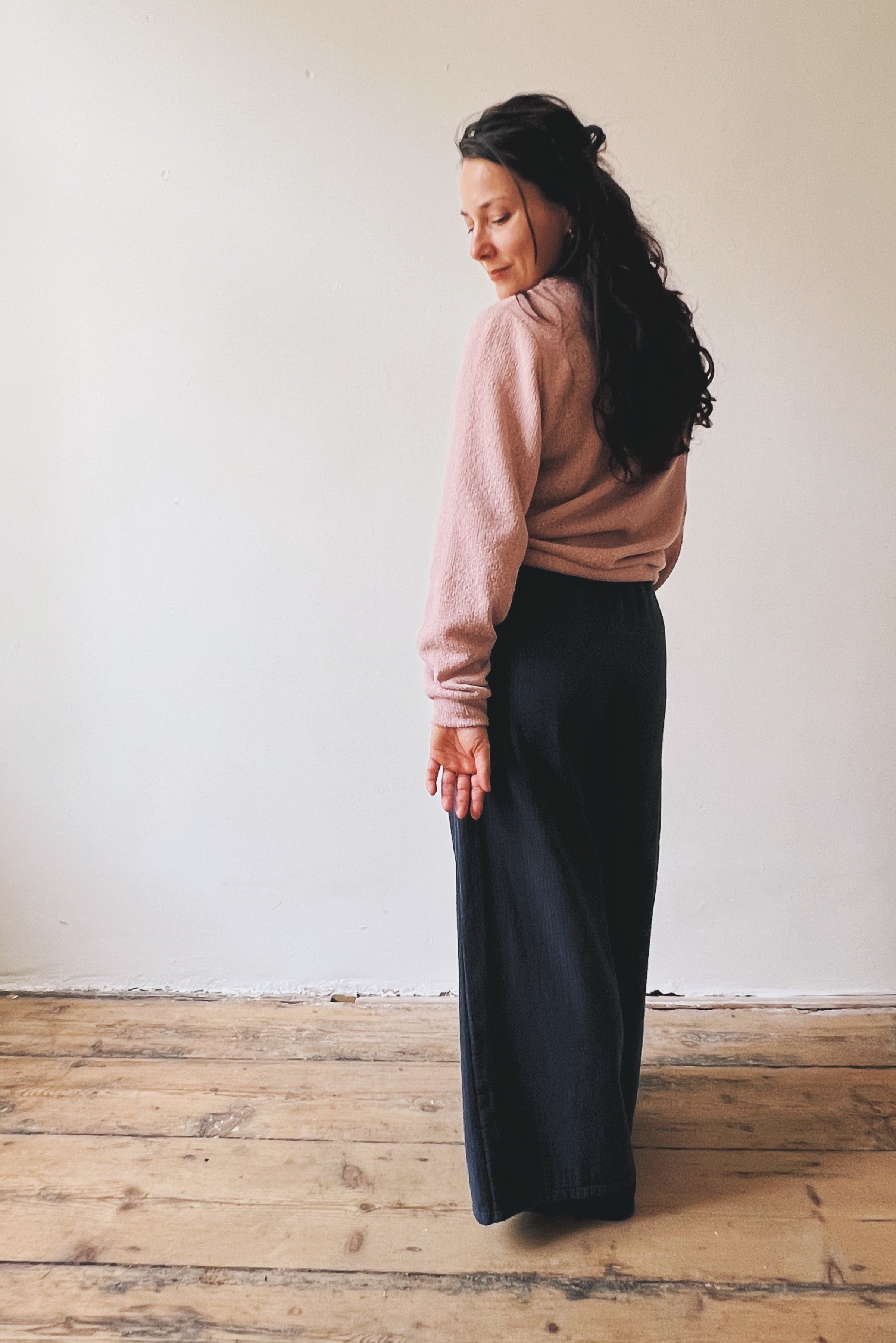 Woman wearing a pink sweater and dark blue wide pants