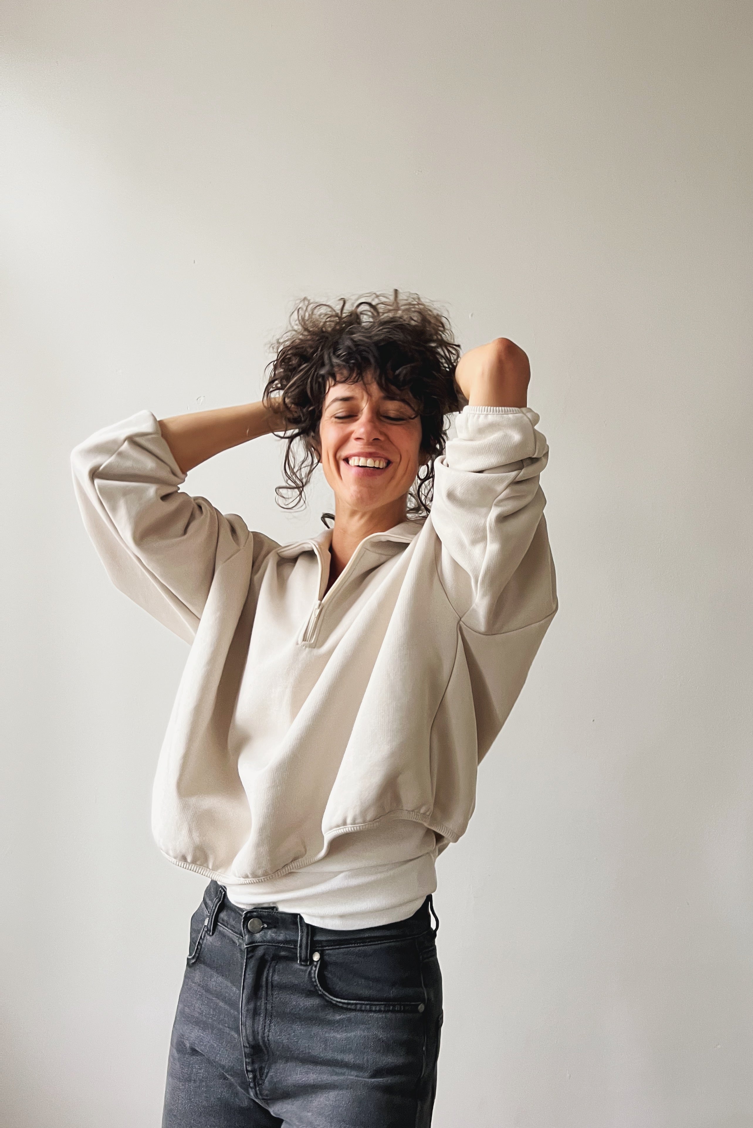 Woman wearing a beige sweater against a plain background