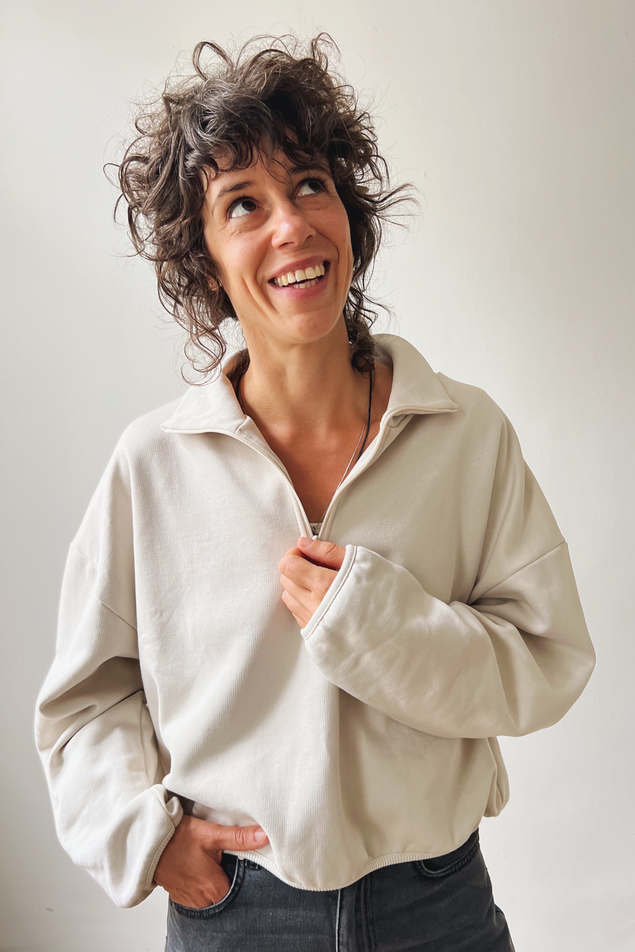 Woman wearing a beige sweater against a plain background