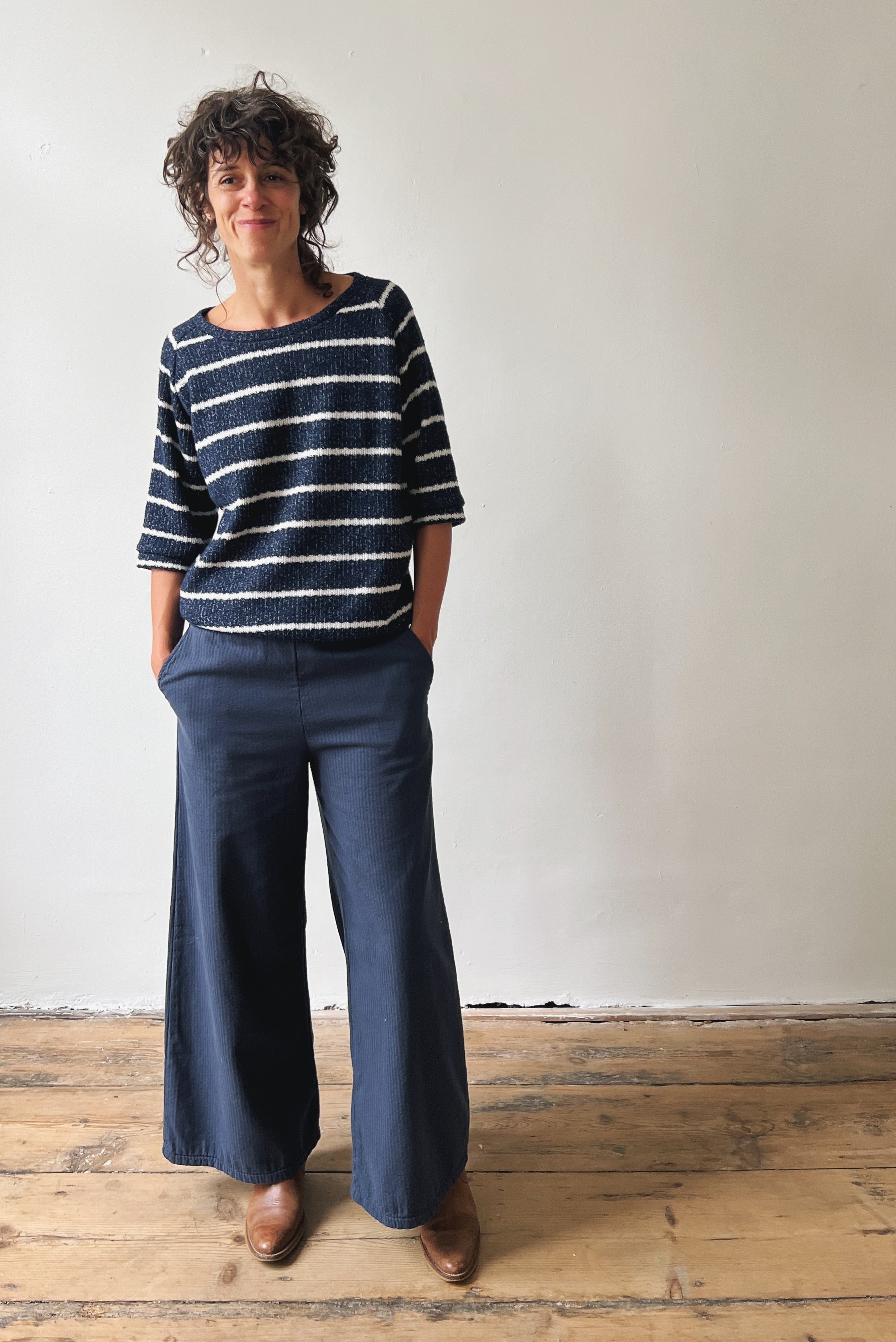 Woman wearing a blue-white striped midsleeve sweater and wide blue pants
