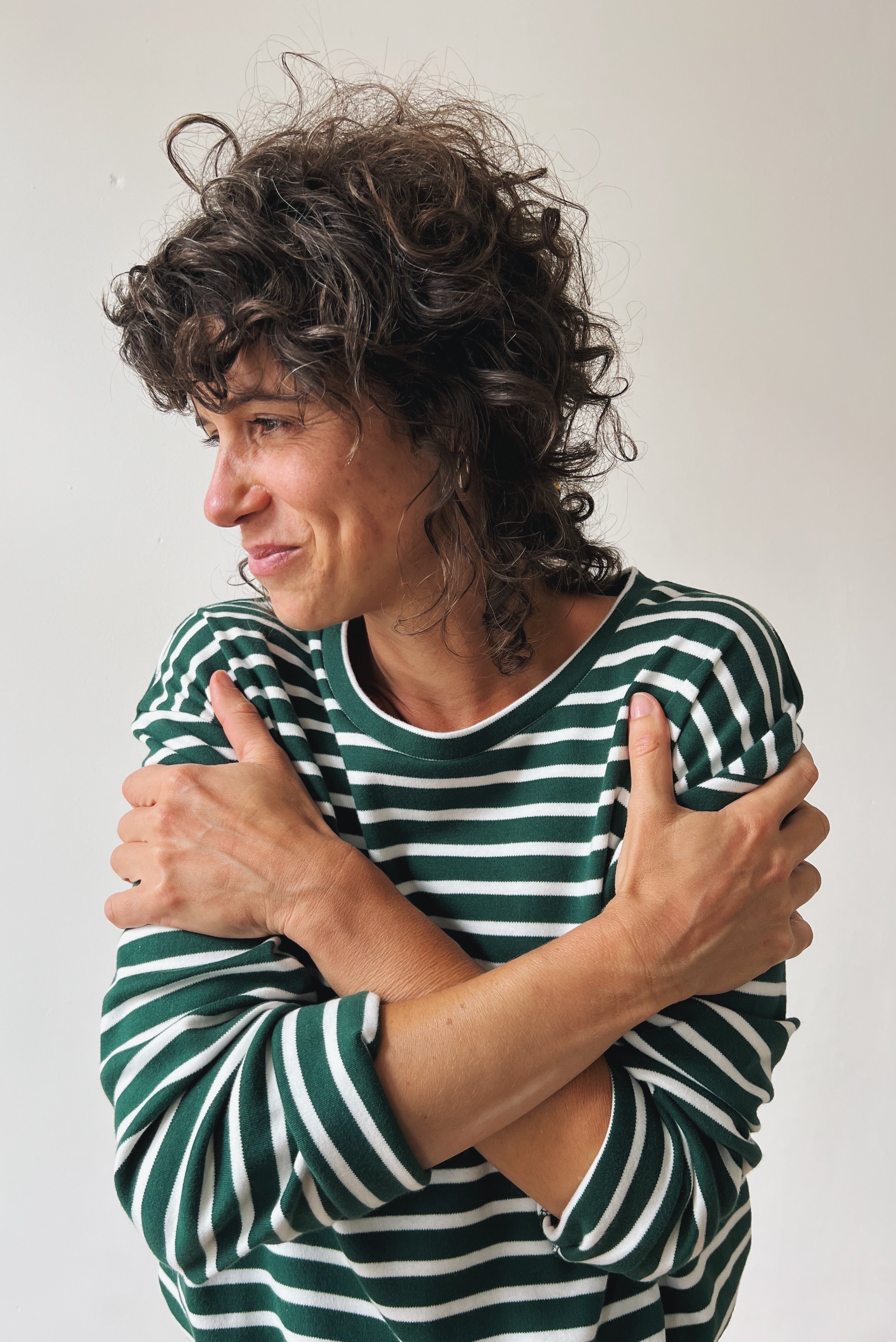 Woman wearing a green and white striped shirt against a plain background