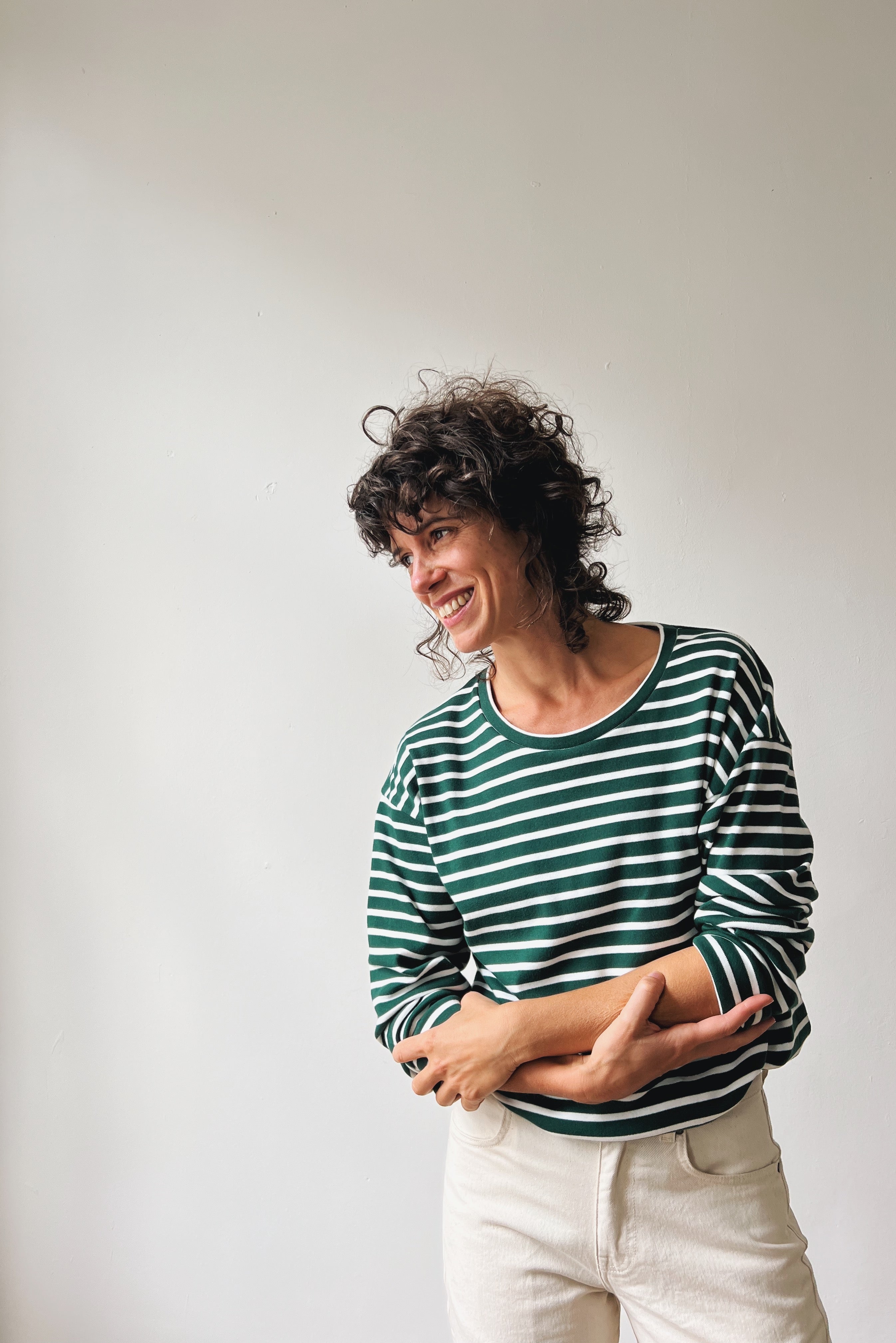 Woman wearing a green and white striped sweater against a plain background