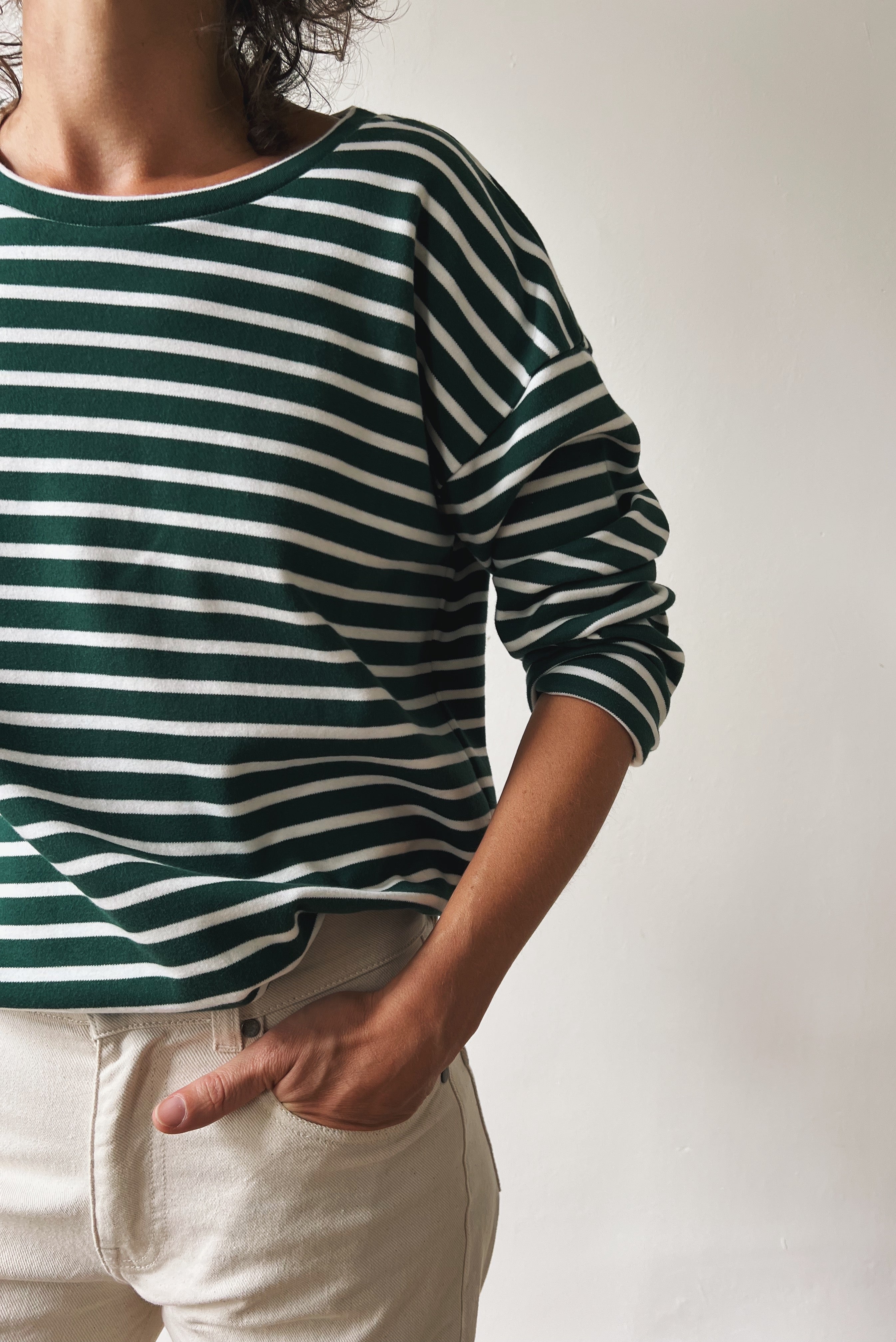 Person wearing a green and white striped sweater with a neutral background