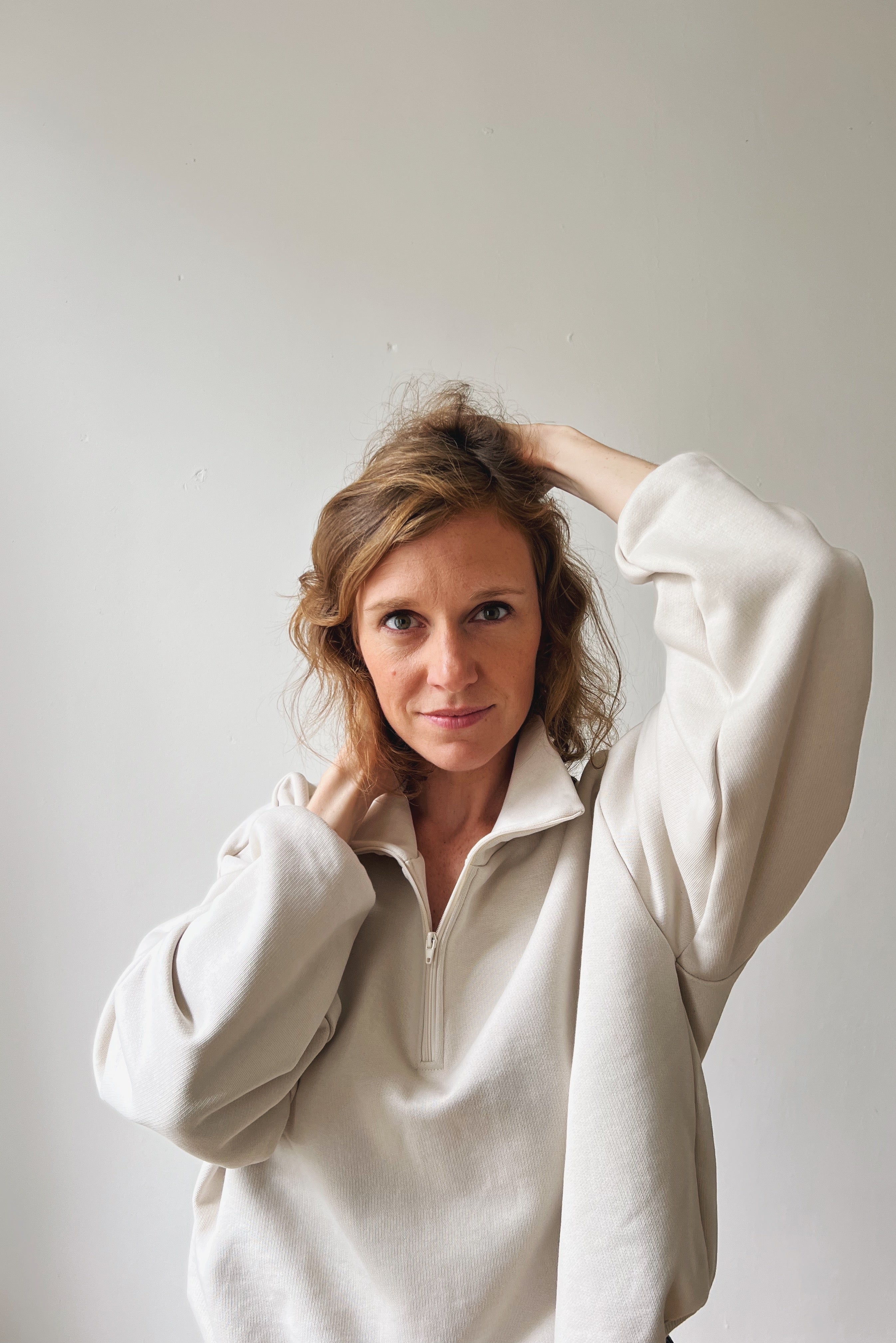 Woman wearing a beige sweater against a plain background