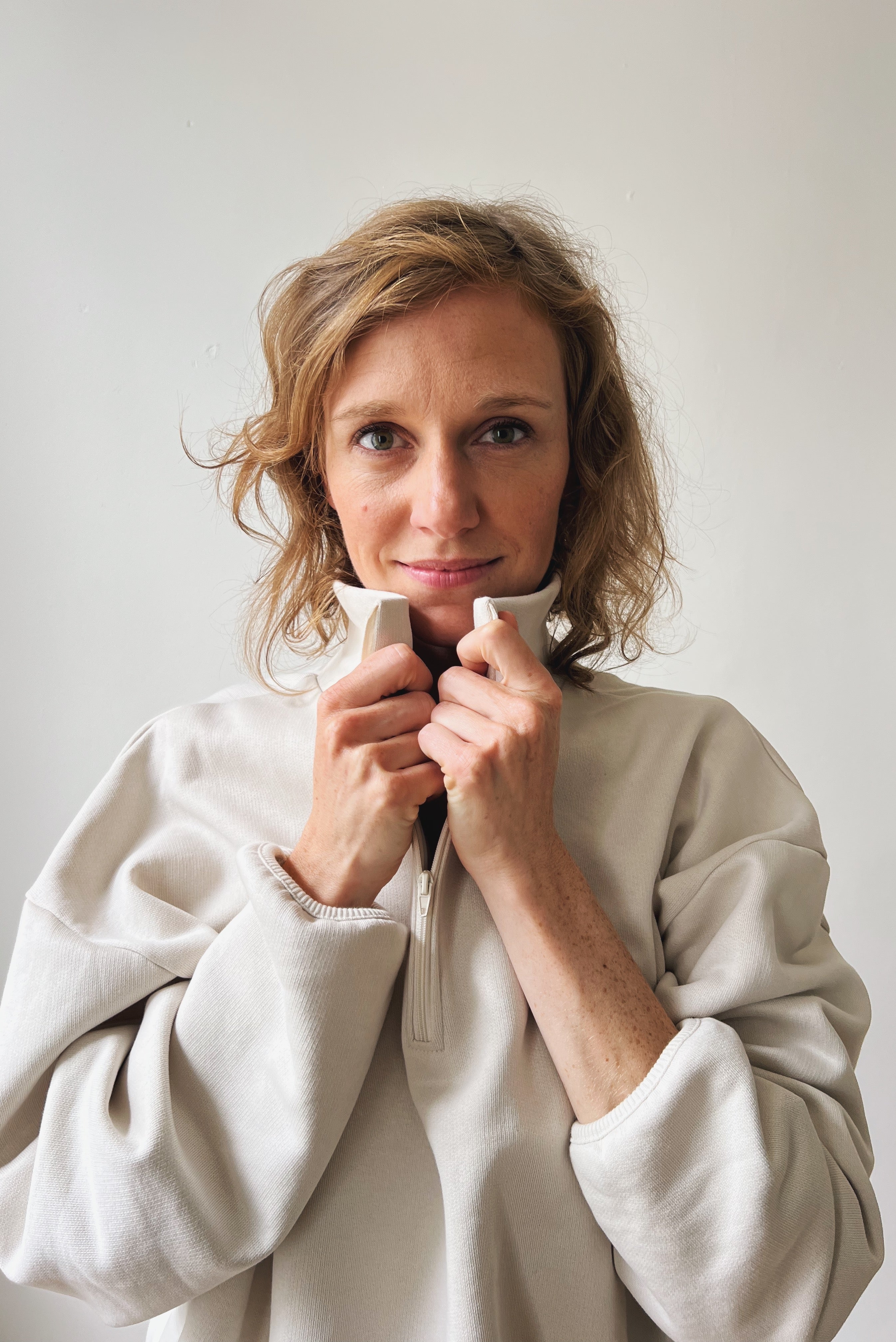 Woman wearing a beige sweater against a plain background