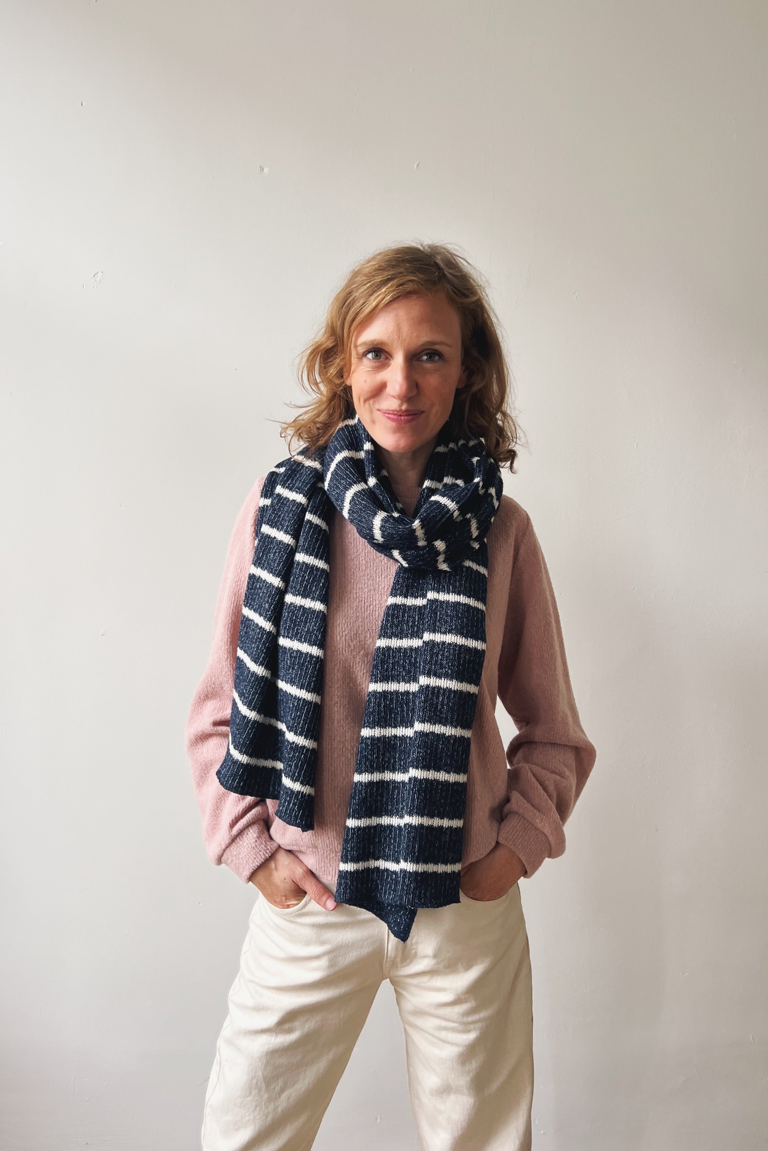 Woman wearing a navy striped scarf against a plain background