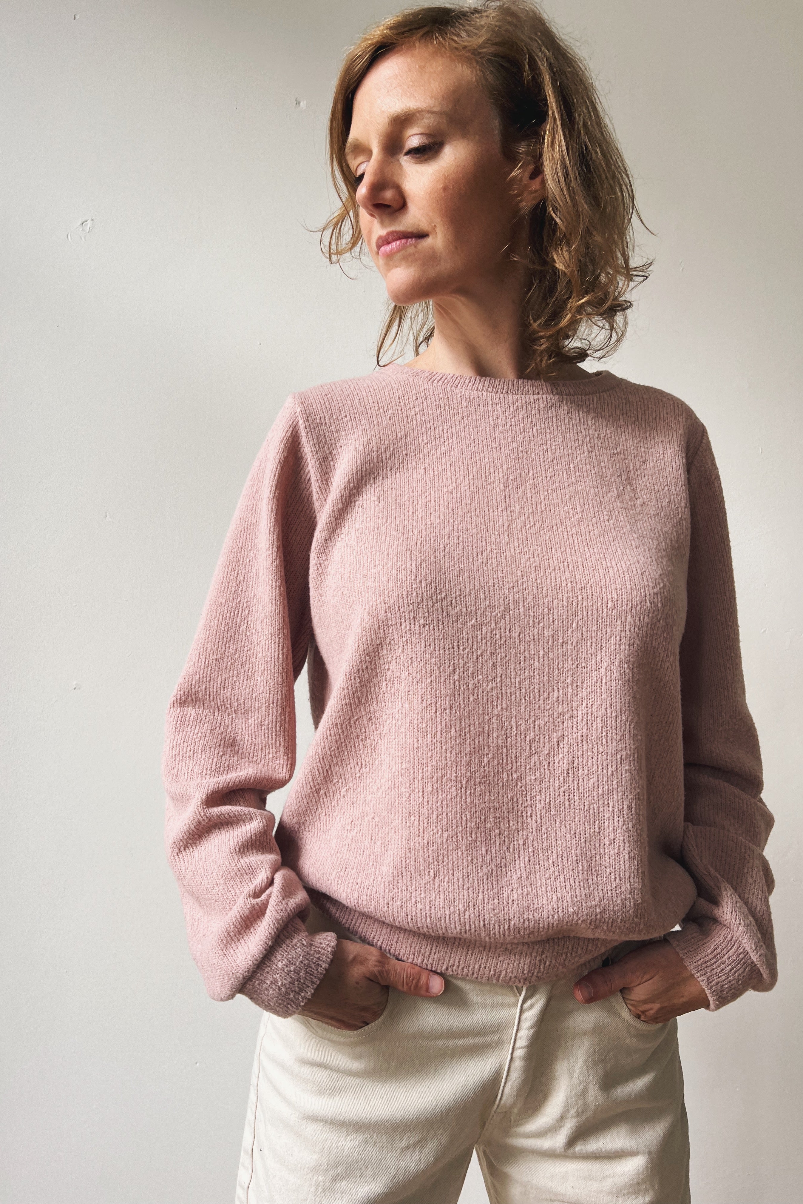 Woman wearing a pink sweater against a plain background