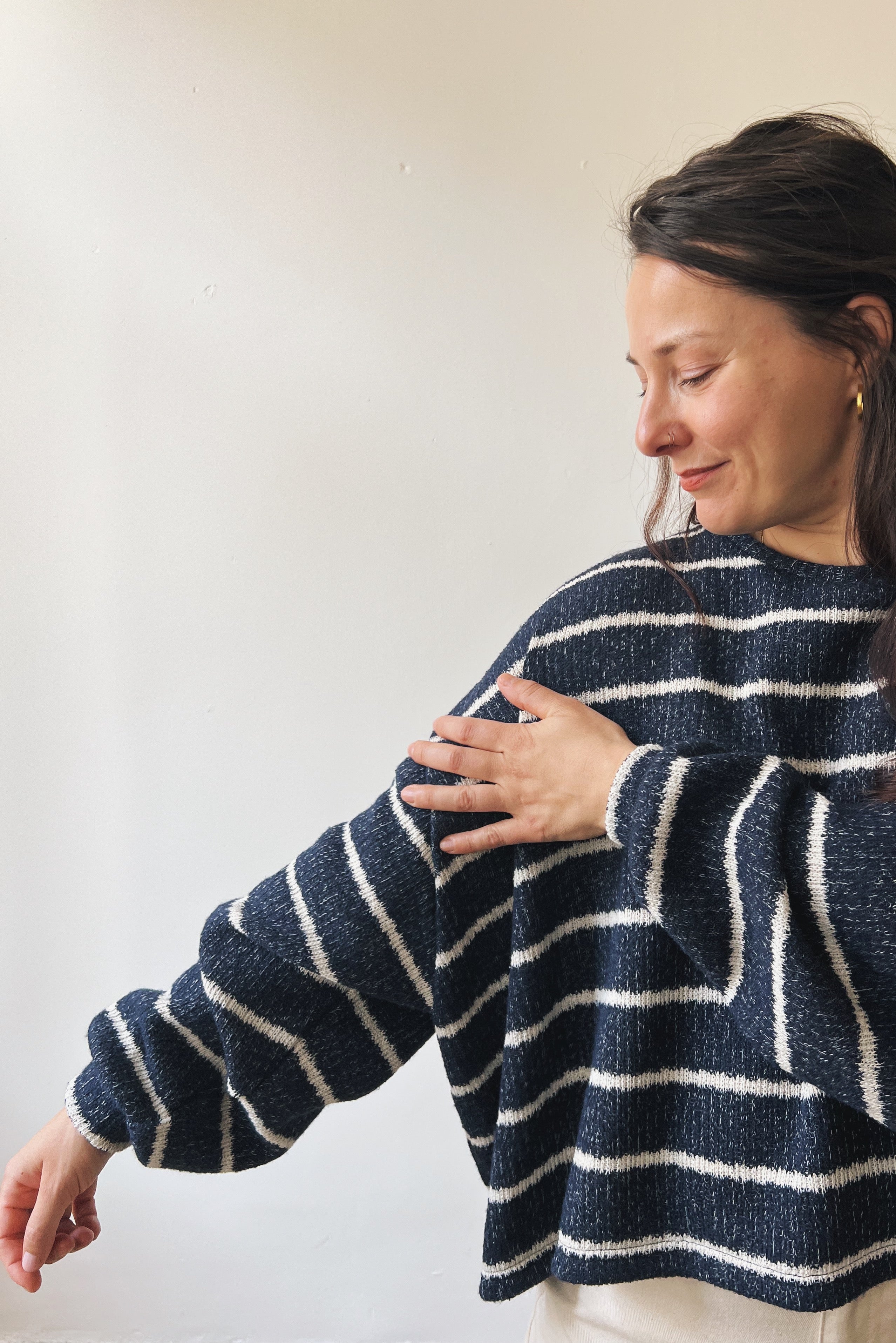 Woman wearing a blue and white striped sweater against a plain background