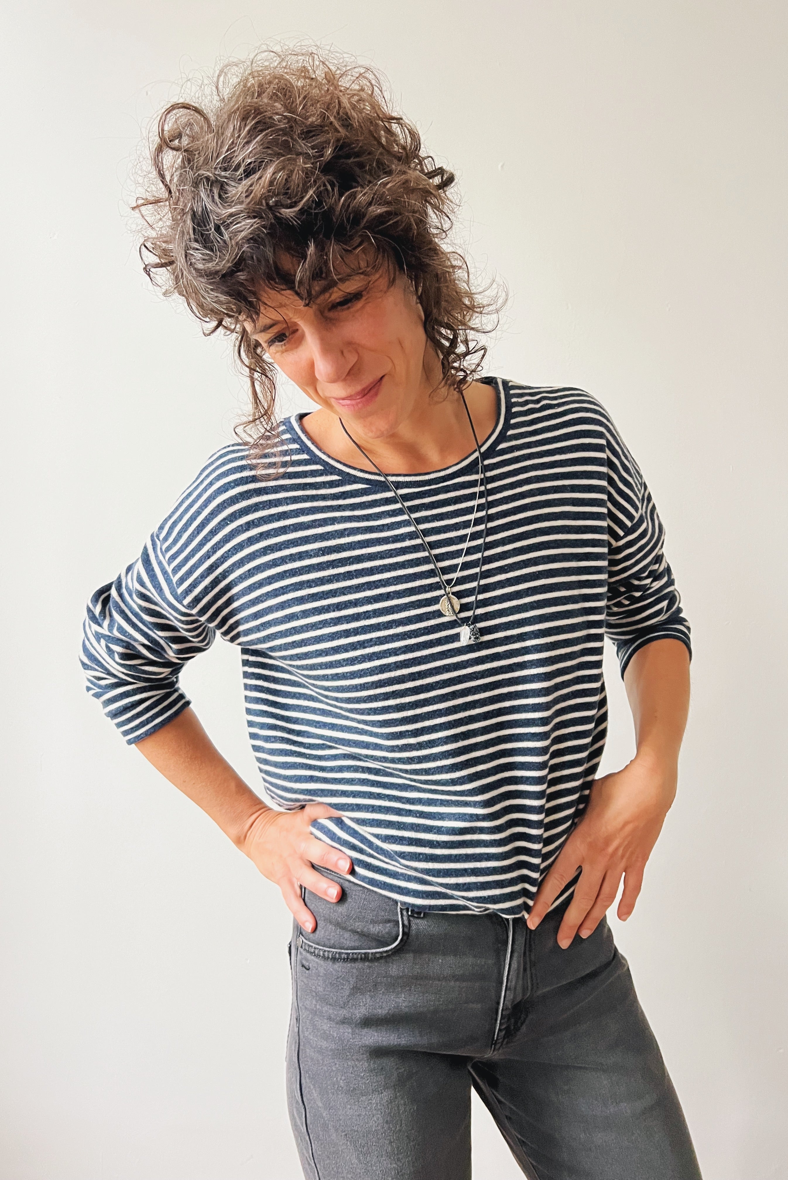 Woman wearing a striped sweater and jeans against a plain background