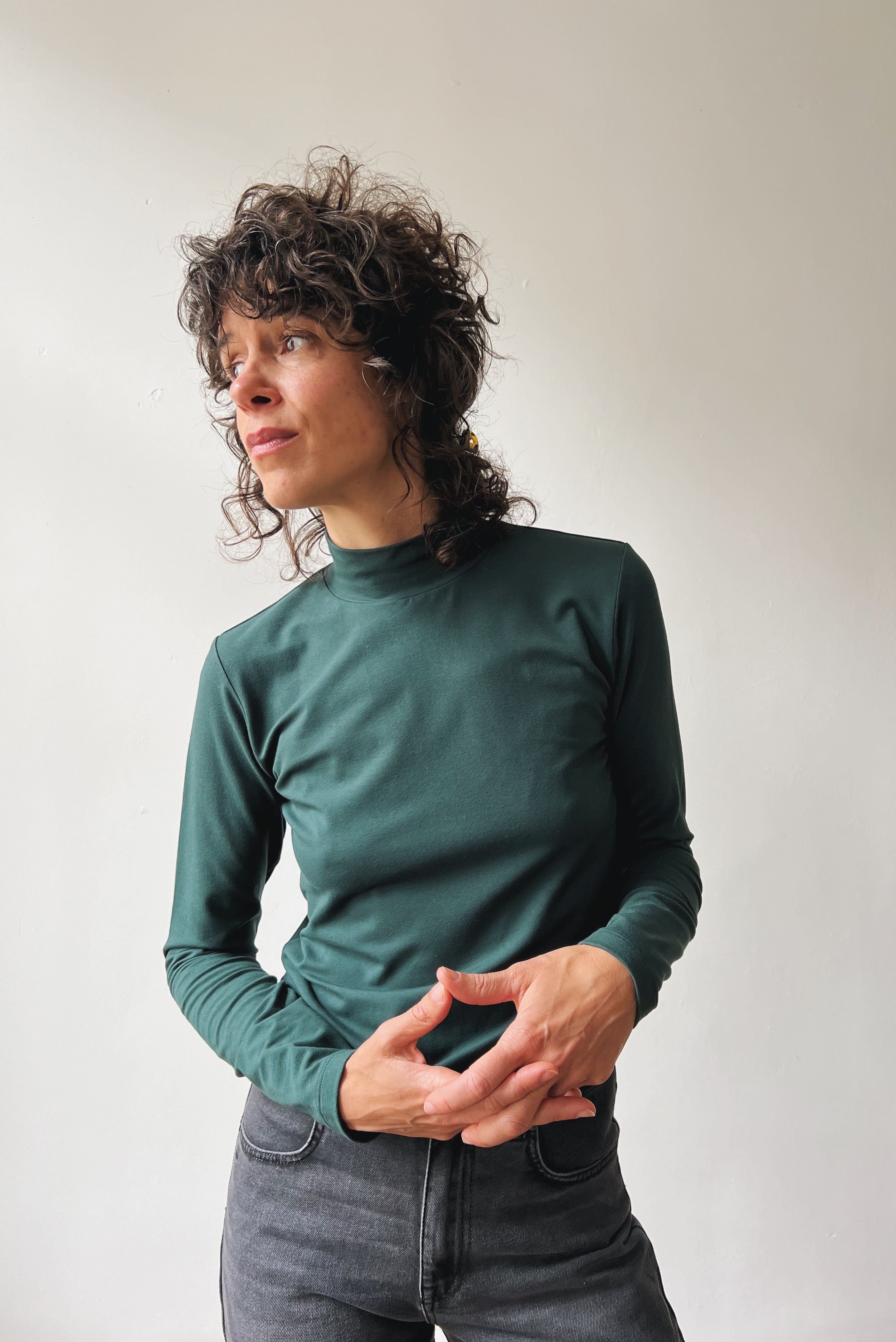 Person wearing a pine turtleneck shirt against a plain background