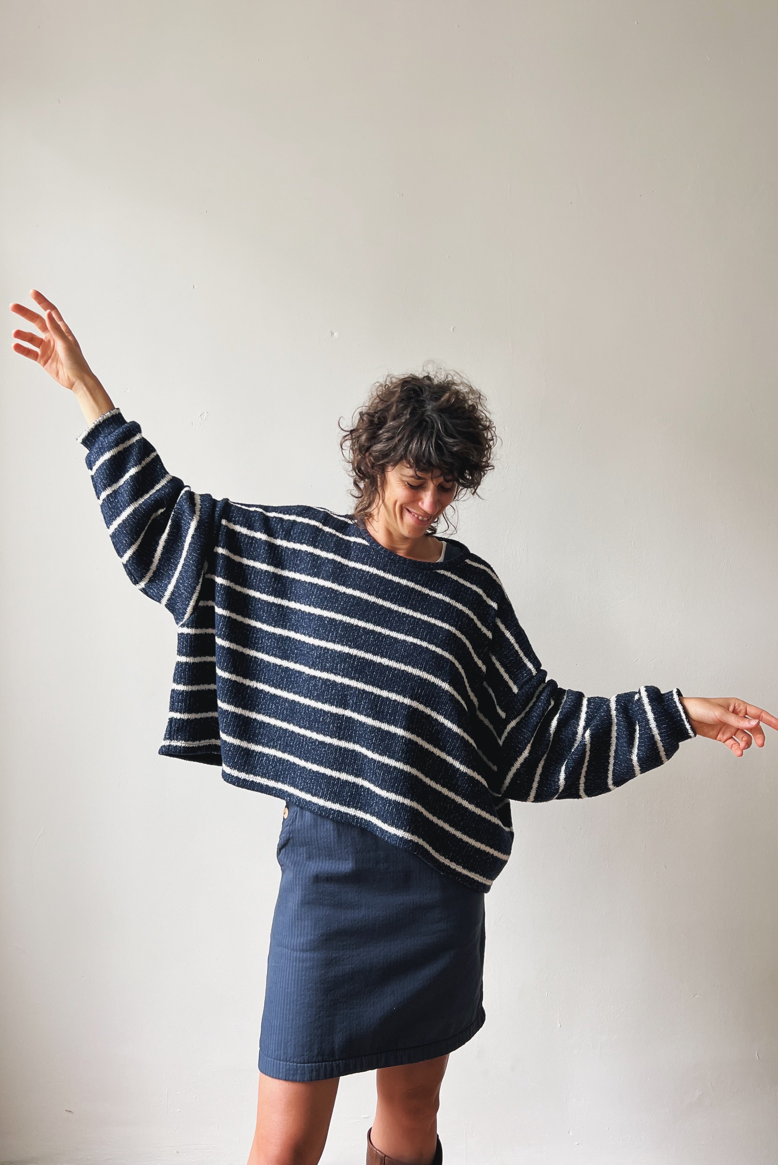 Person wearing a blue and white striped sweater and blue skirt