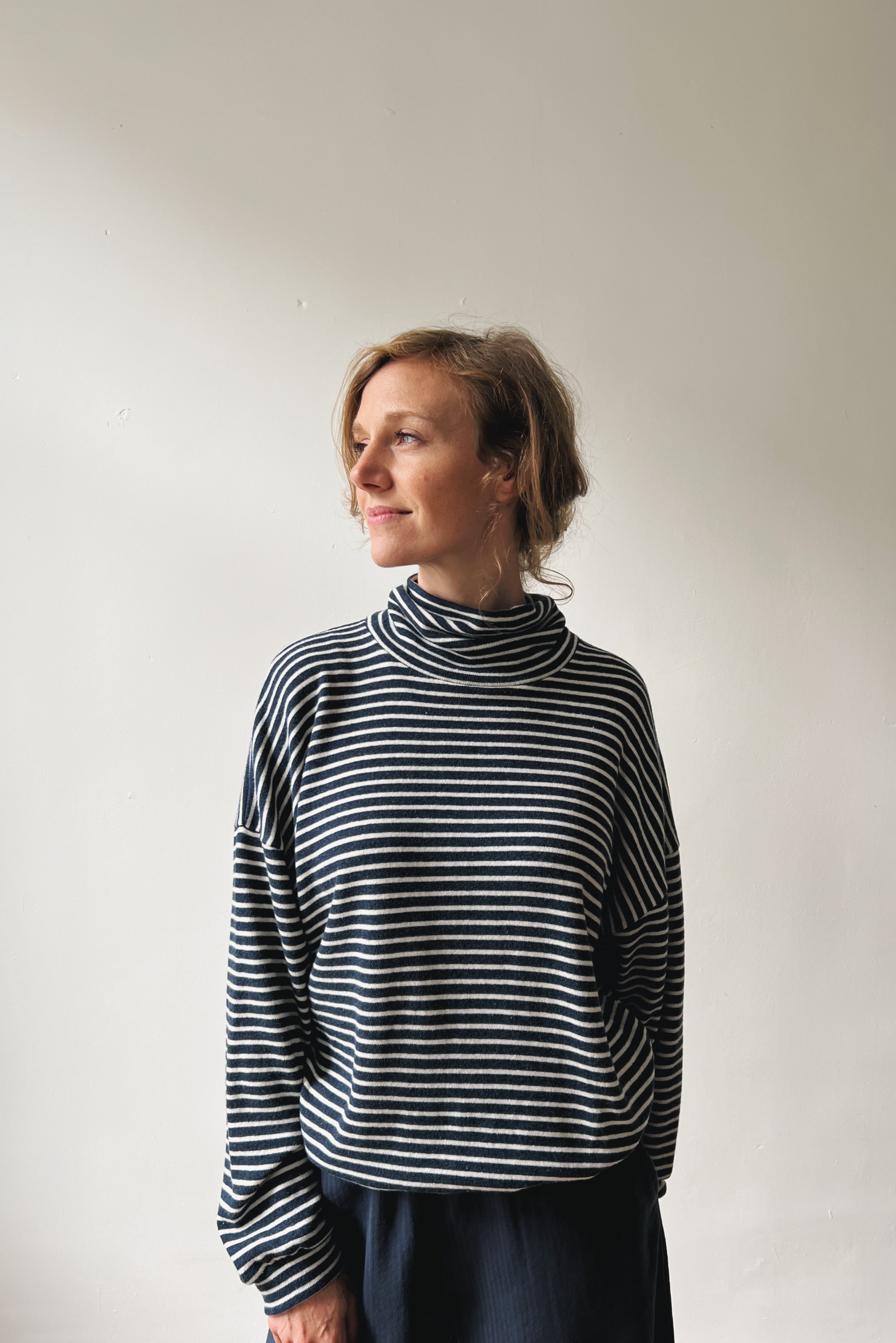 Woman wearing a blue and white striped sweater against a plain background