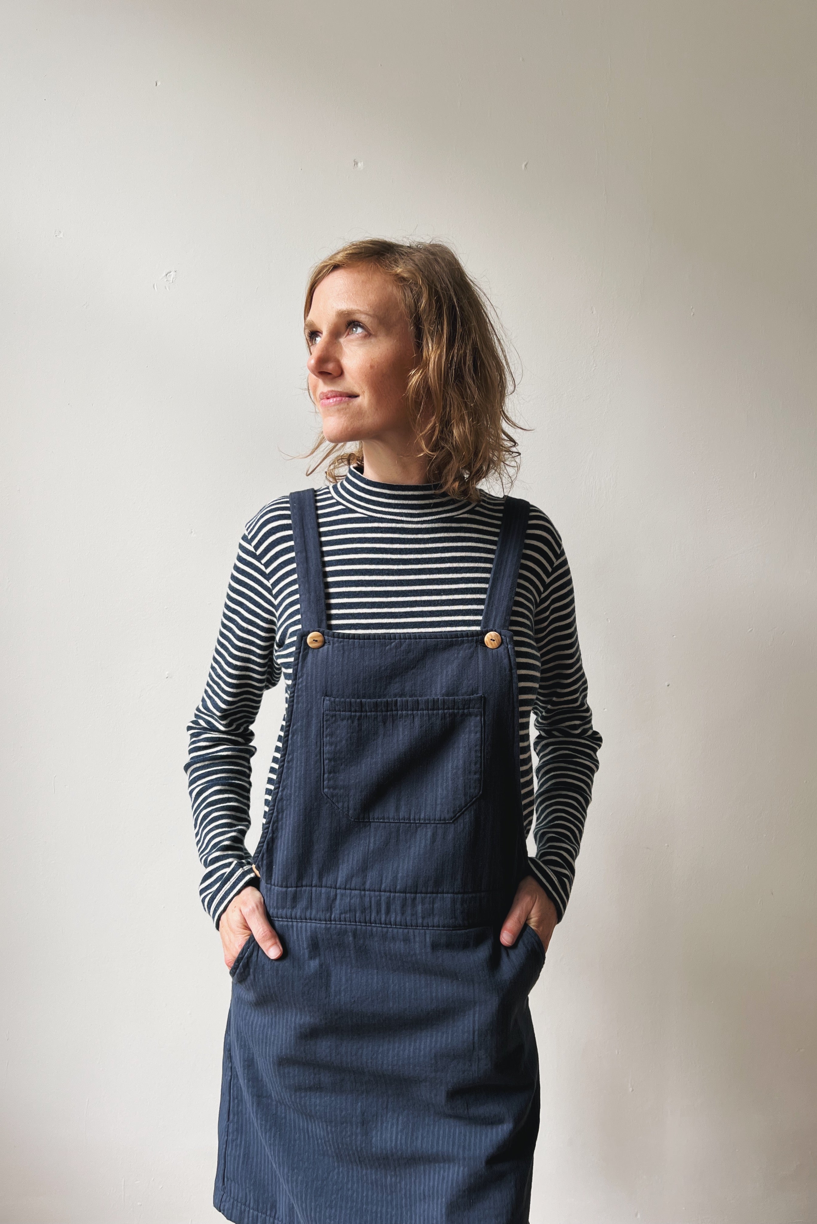 Woman wearing a blue-white striped turtleneck and blue salopettedress