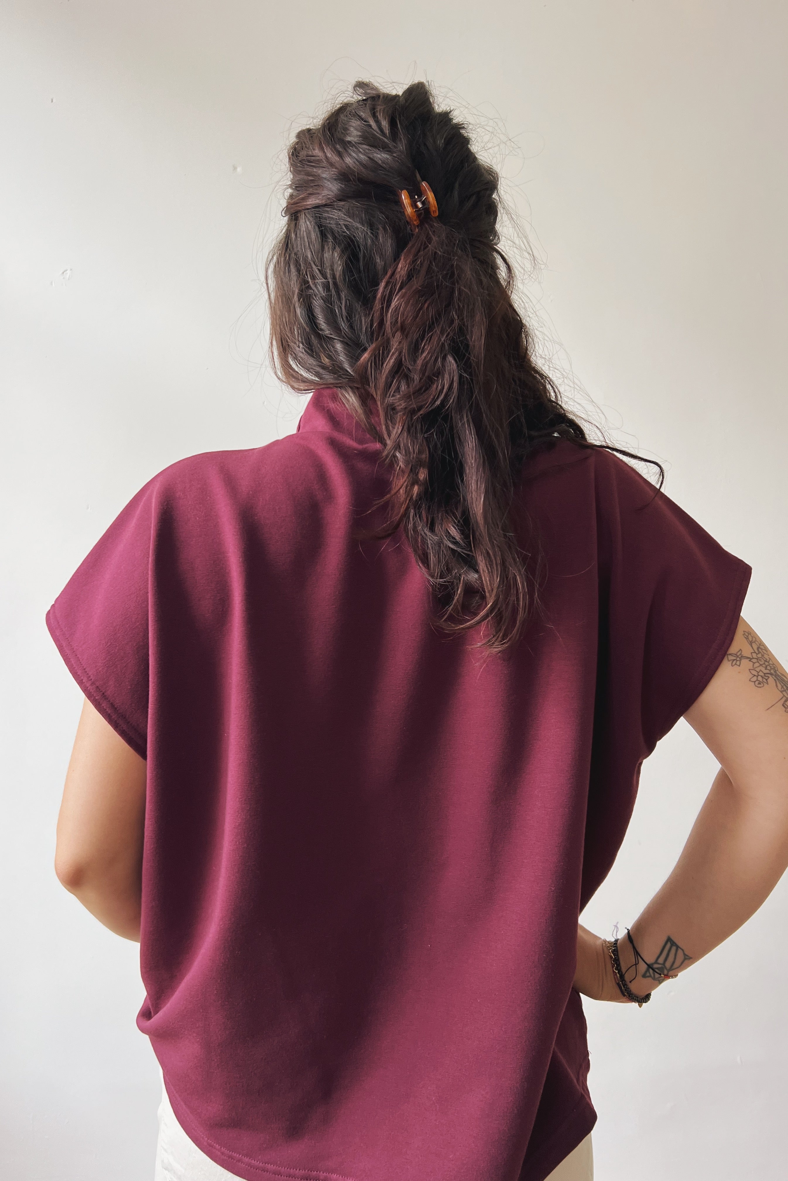 Person wearing an aubergine sleeveless sweater