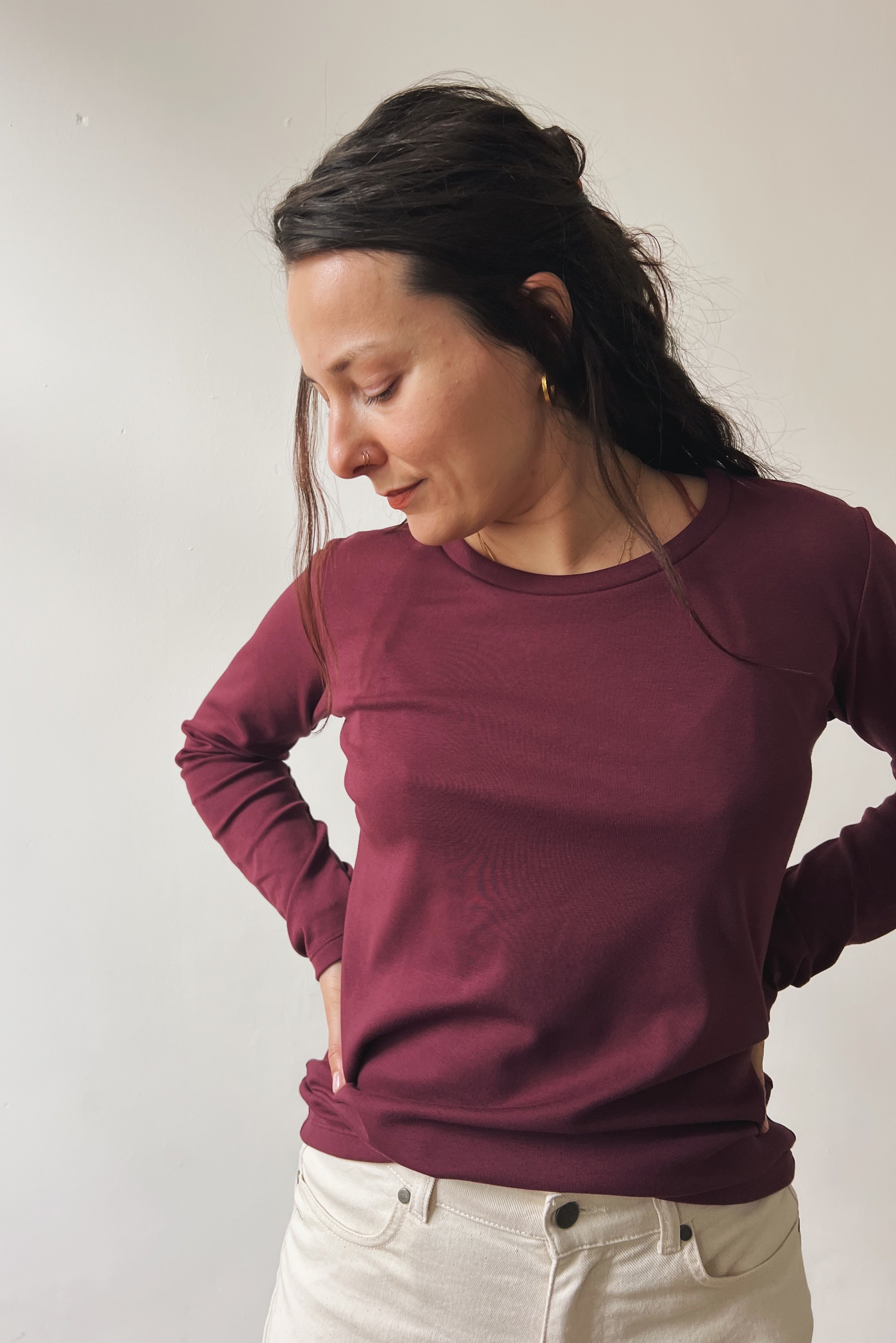 Woman wearing an aubergine longsleeve against a plain background