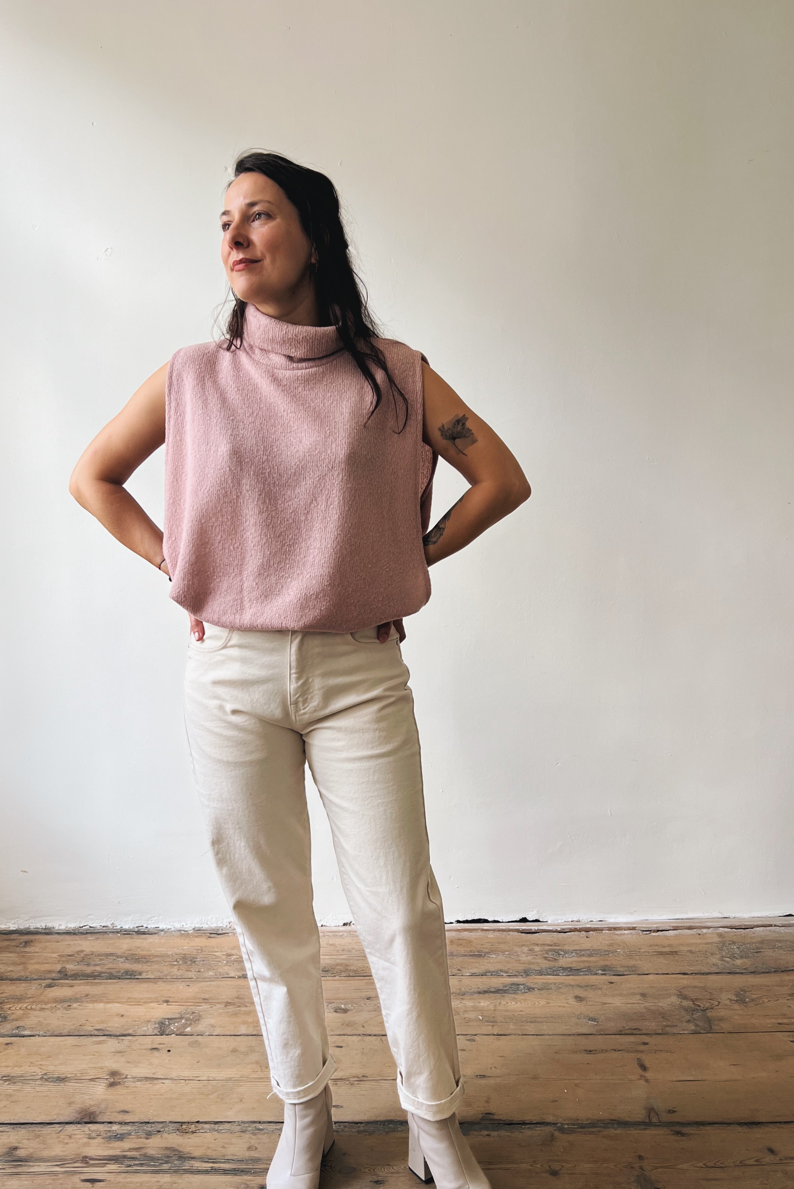 Woman wearing a pink sleeveless top and an oat boyfriend jeans.