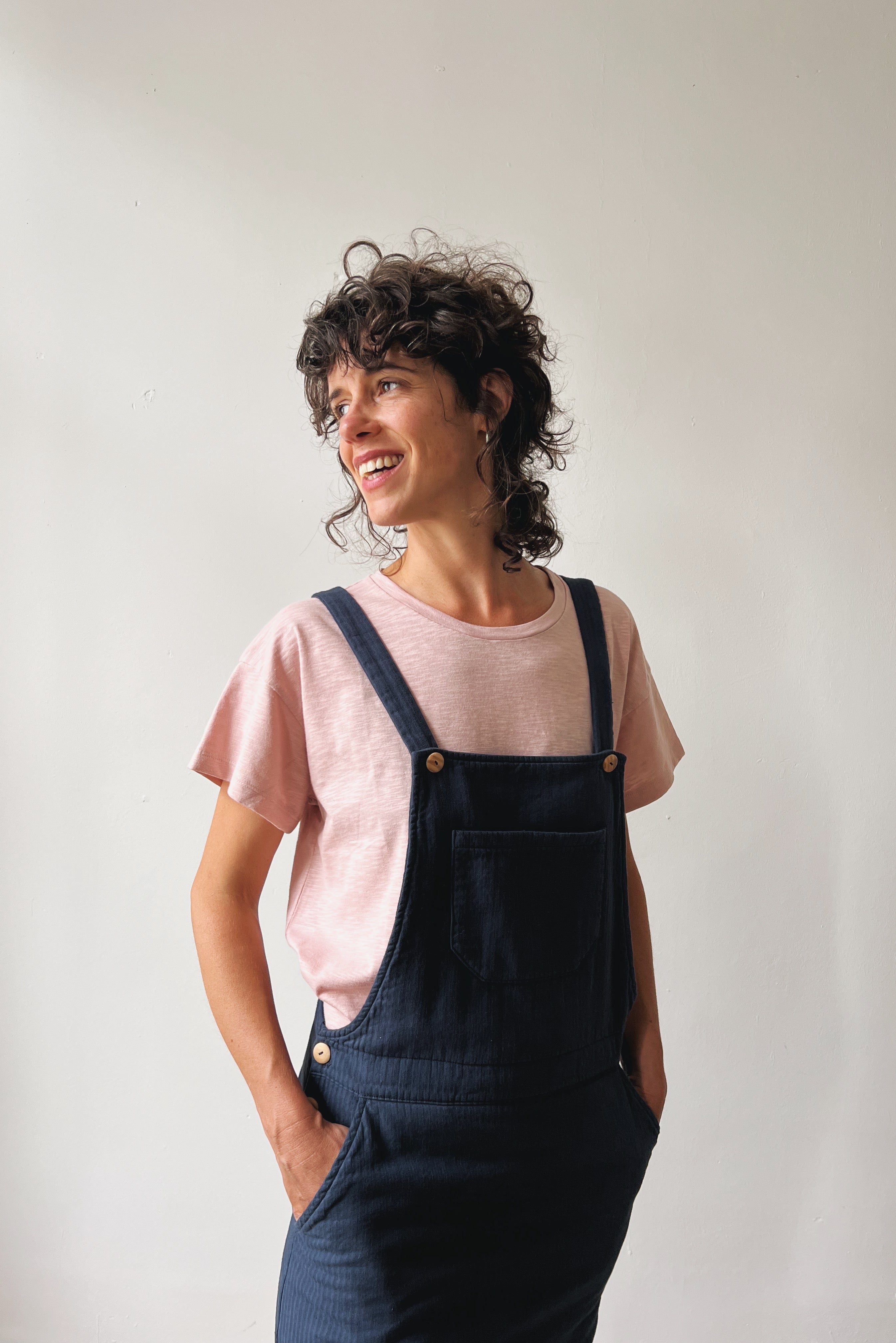 Woman wearing a pink t-shirt and blue salopettedress