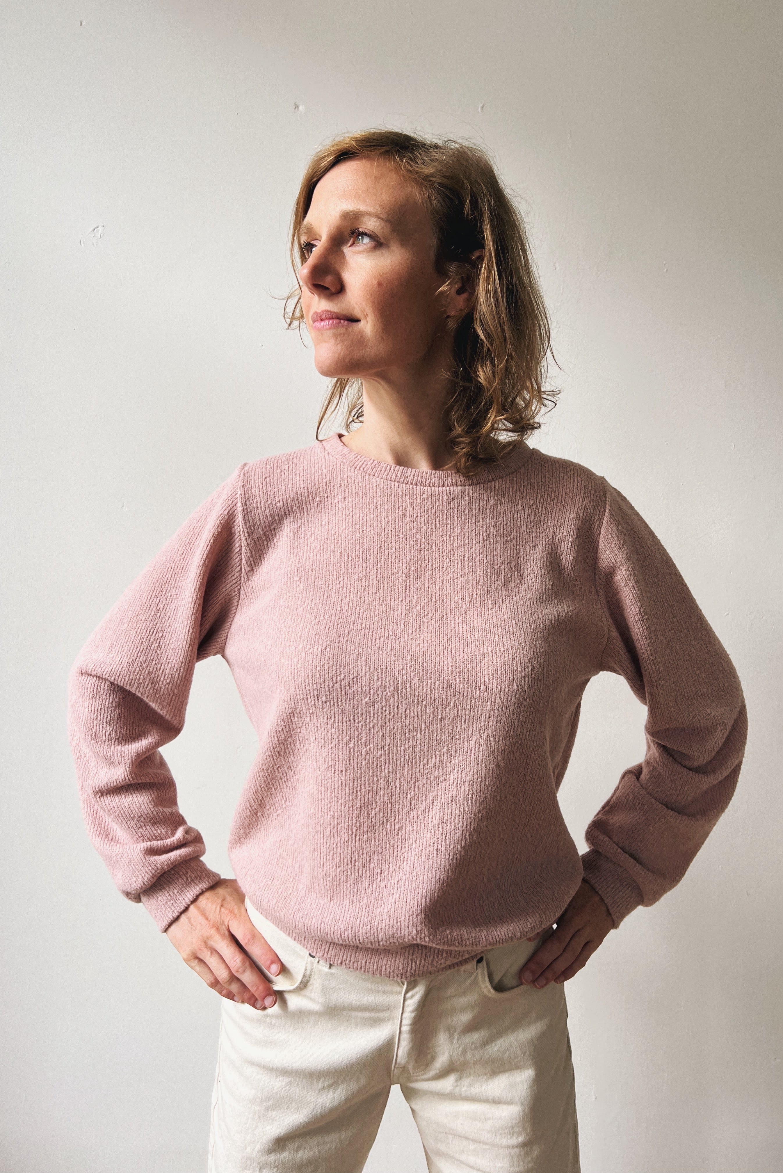 Woman wearing a pink sweater against a plain background