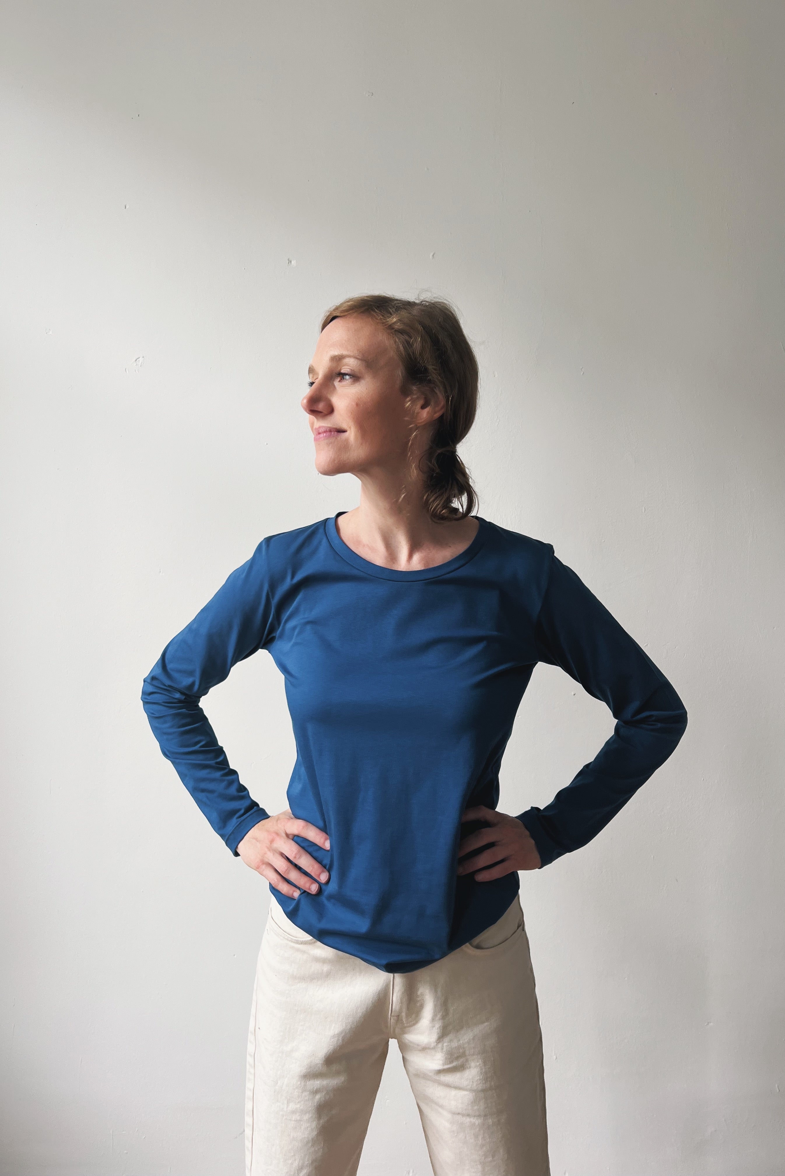 Woman wearing a blue long-sleeve top and oat boyfriend jeans against a plain background